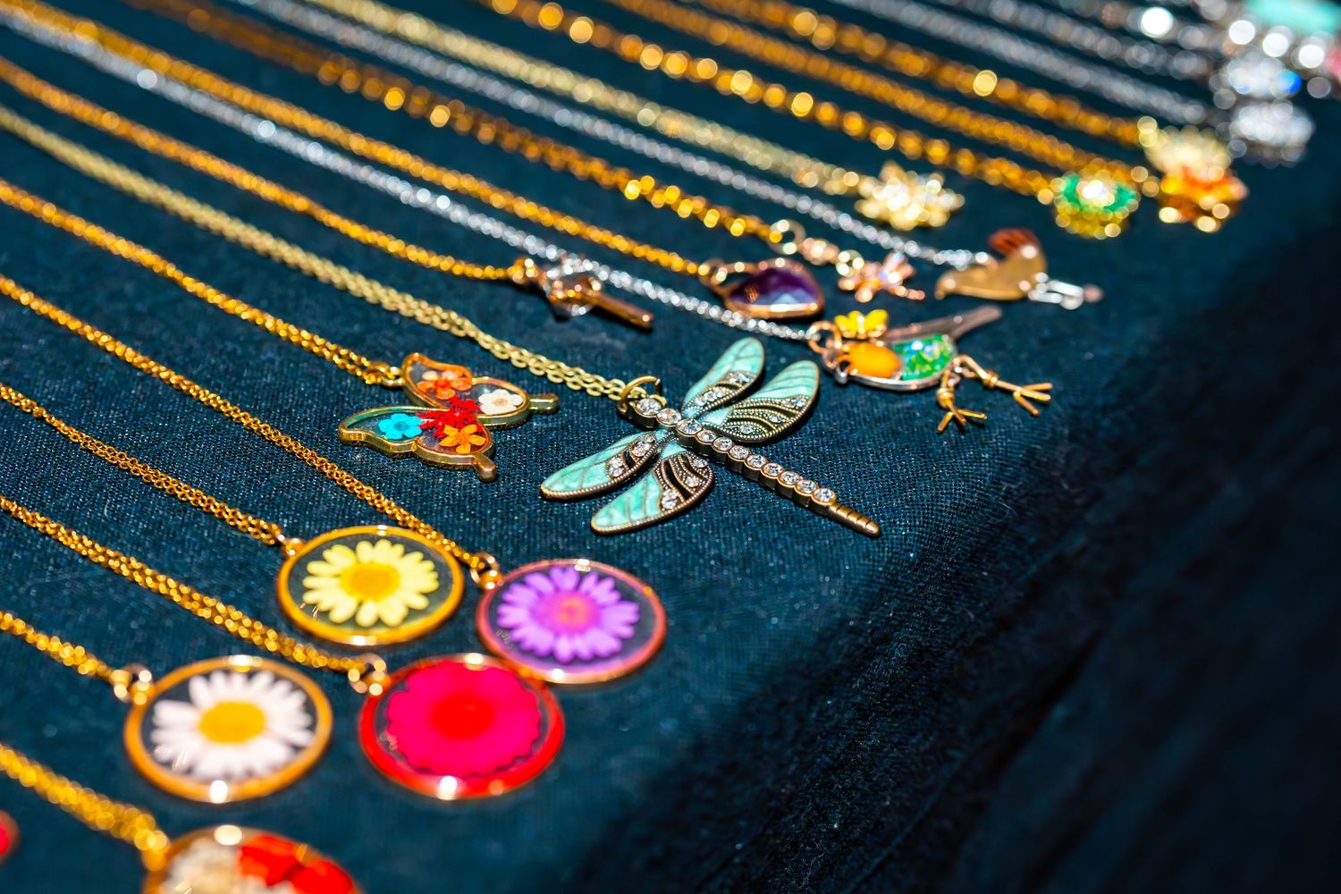 Colorful pendant necklaces with crystal and charm designs displayed at indoor marketplace.