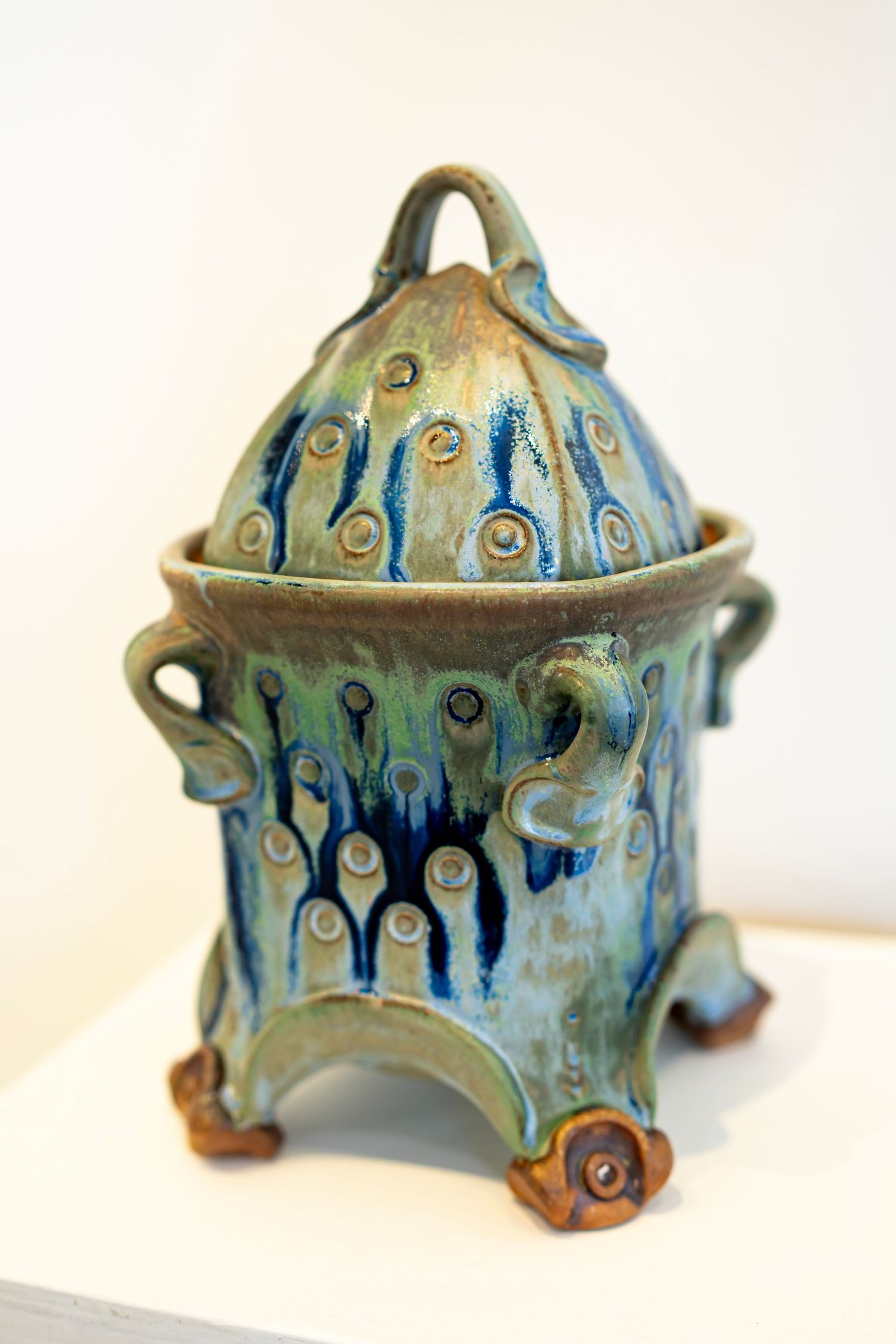 Handcrafted ceramic bowl with blue glaze and decorative drip pattern design displayed at art show.
