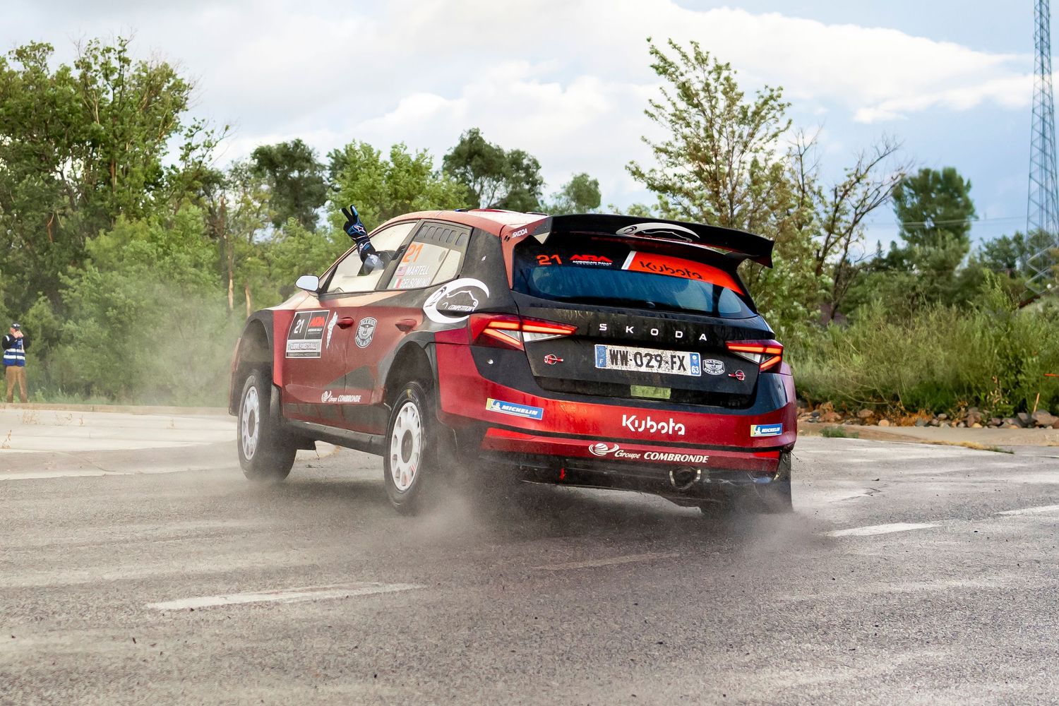 Rally cars kicking up dirt and dust while racing on gravel track.