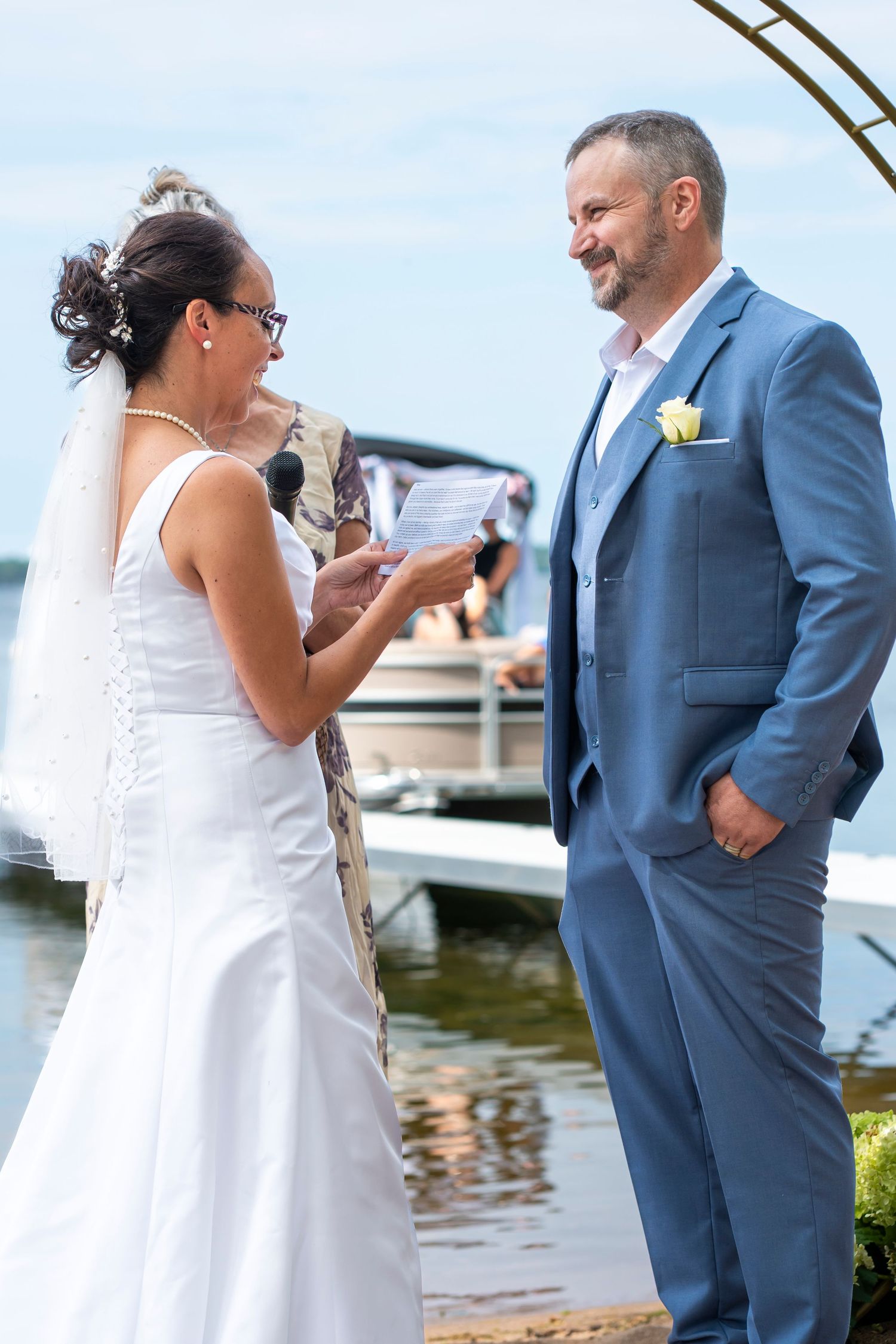 Bride and groom sharing vows and reactions at lakeside wedding.