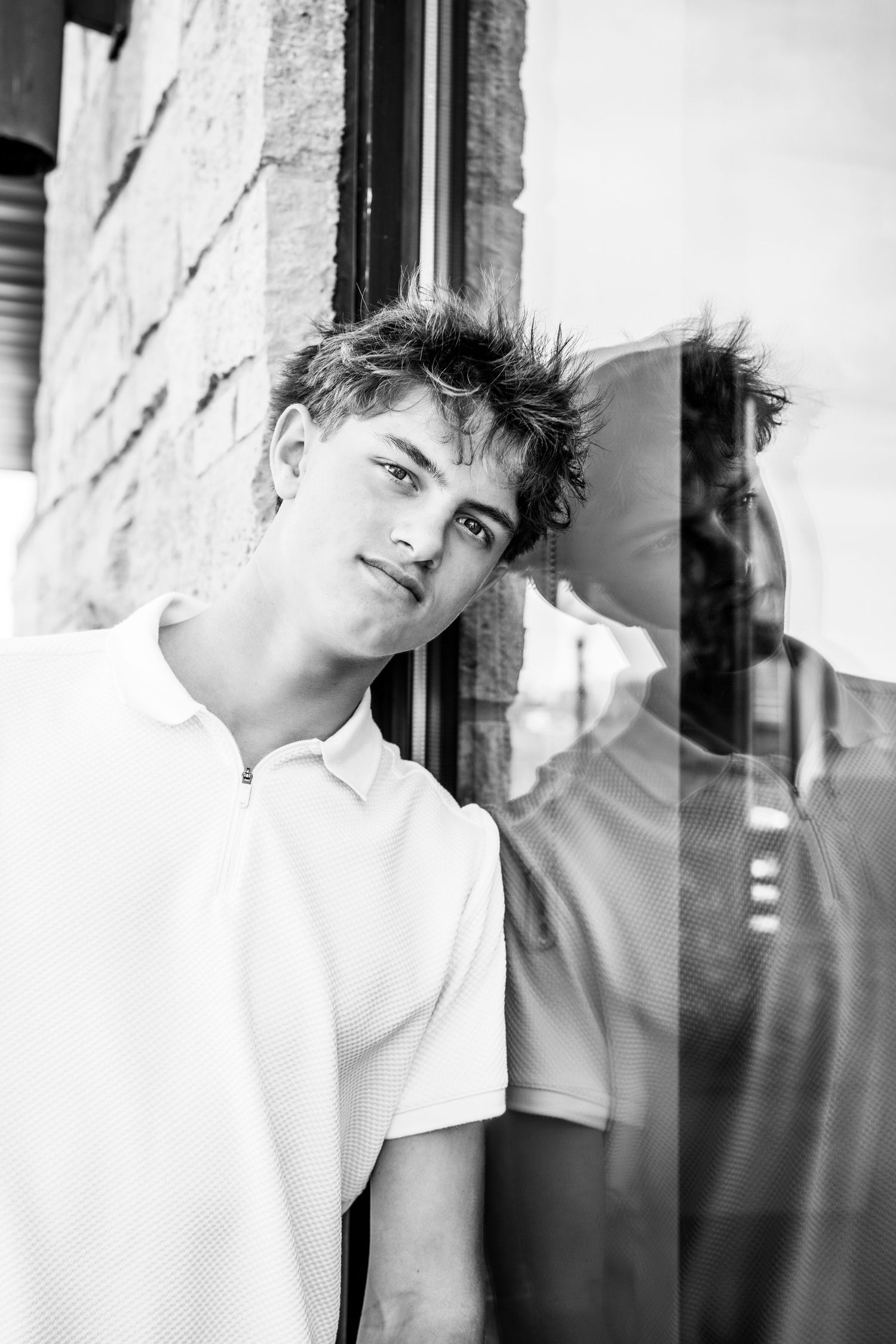 A black and white artistic portrait series showing moody poses against a wall in dramatic lighting.