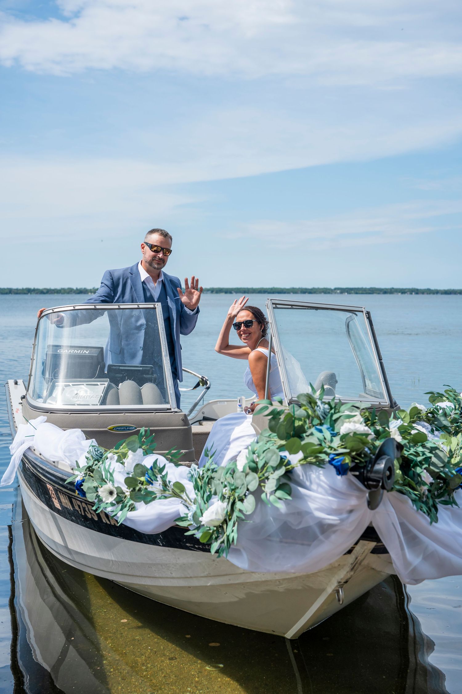 Decorated boat with white fabric and greenery garlands under blue skies.