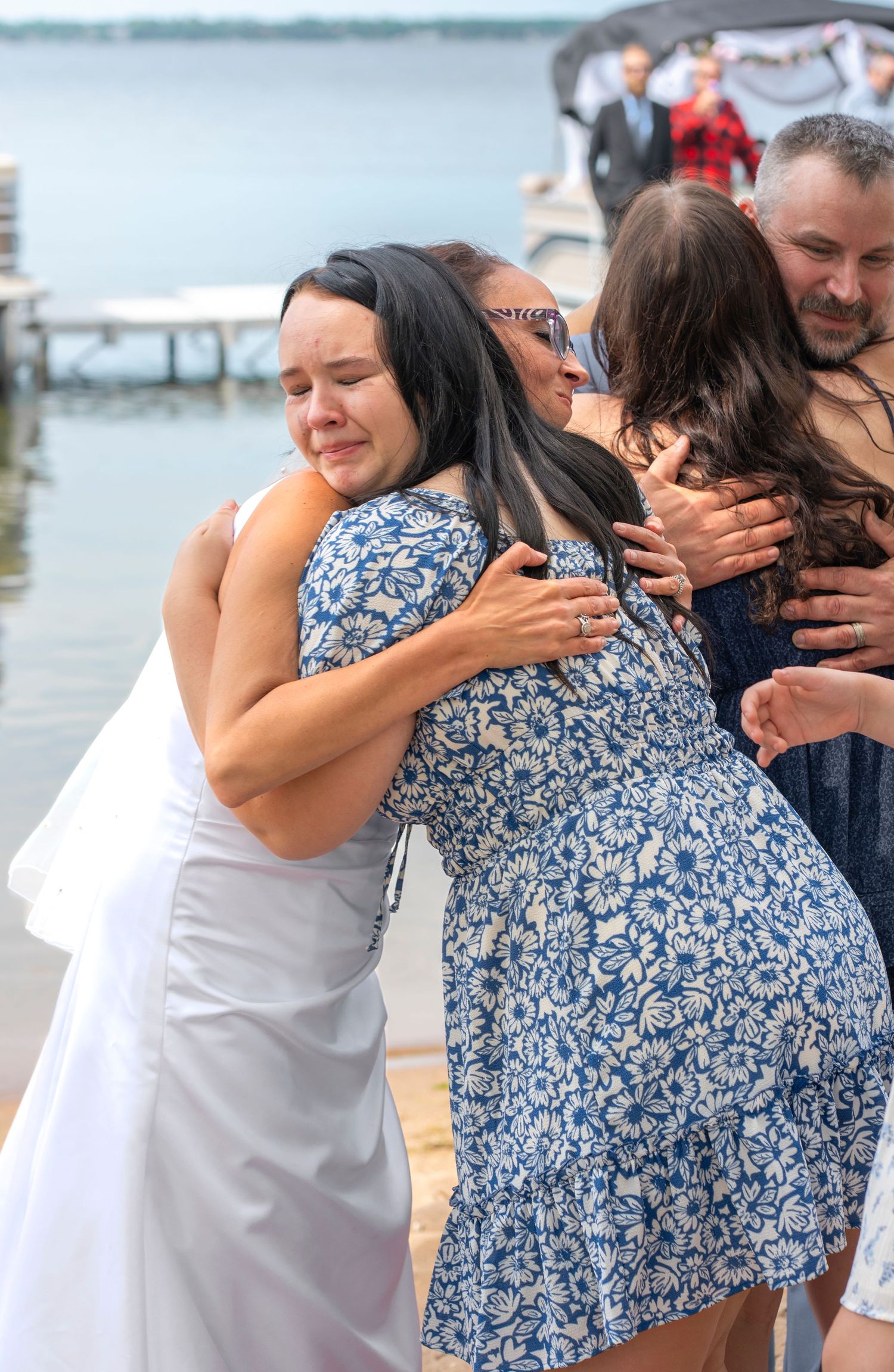 Joyful group hug during waterfront wedding celebration.
