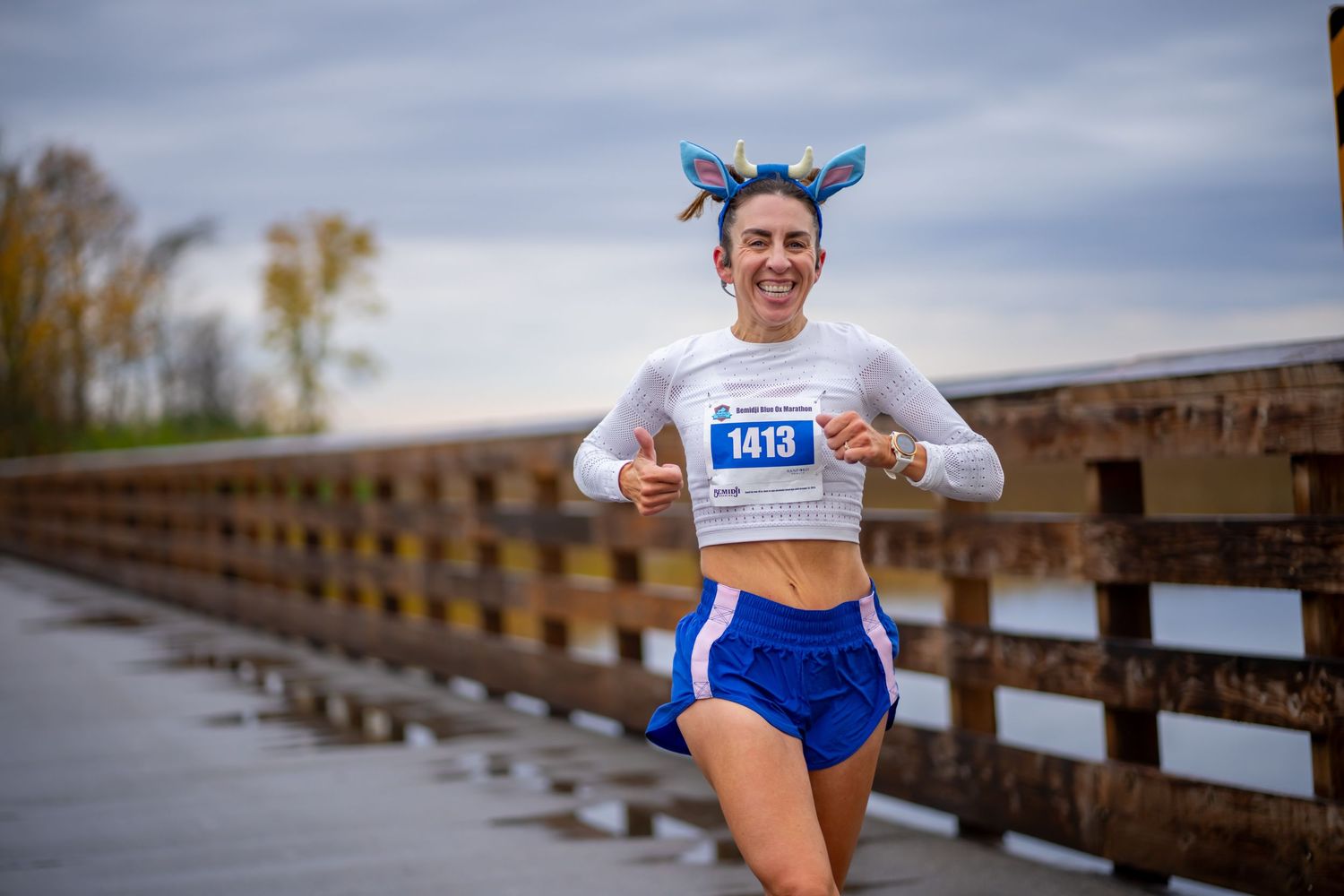 Runner in athletic gear jogging along a wooden boardwalk path during autumn.