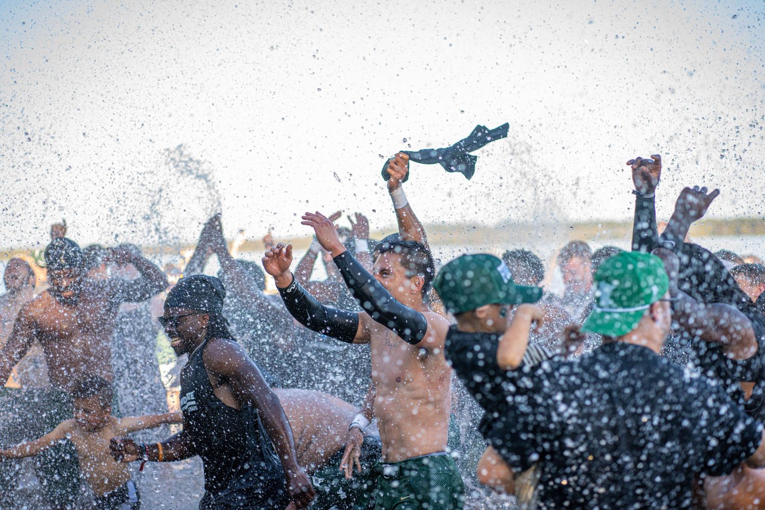 Water droplets spraying over excited crowd during outdoor celebration after football game.