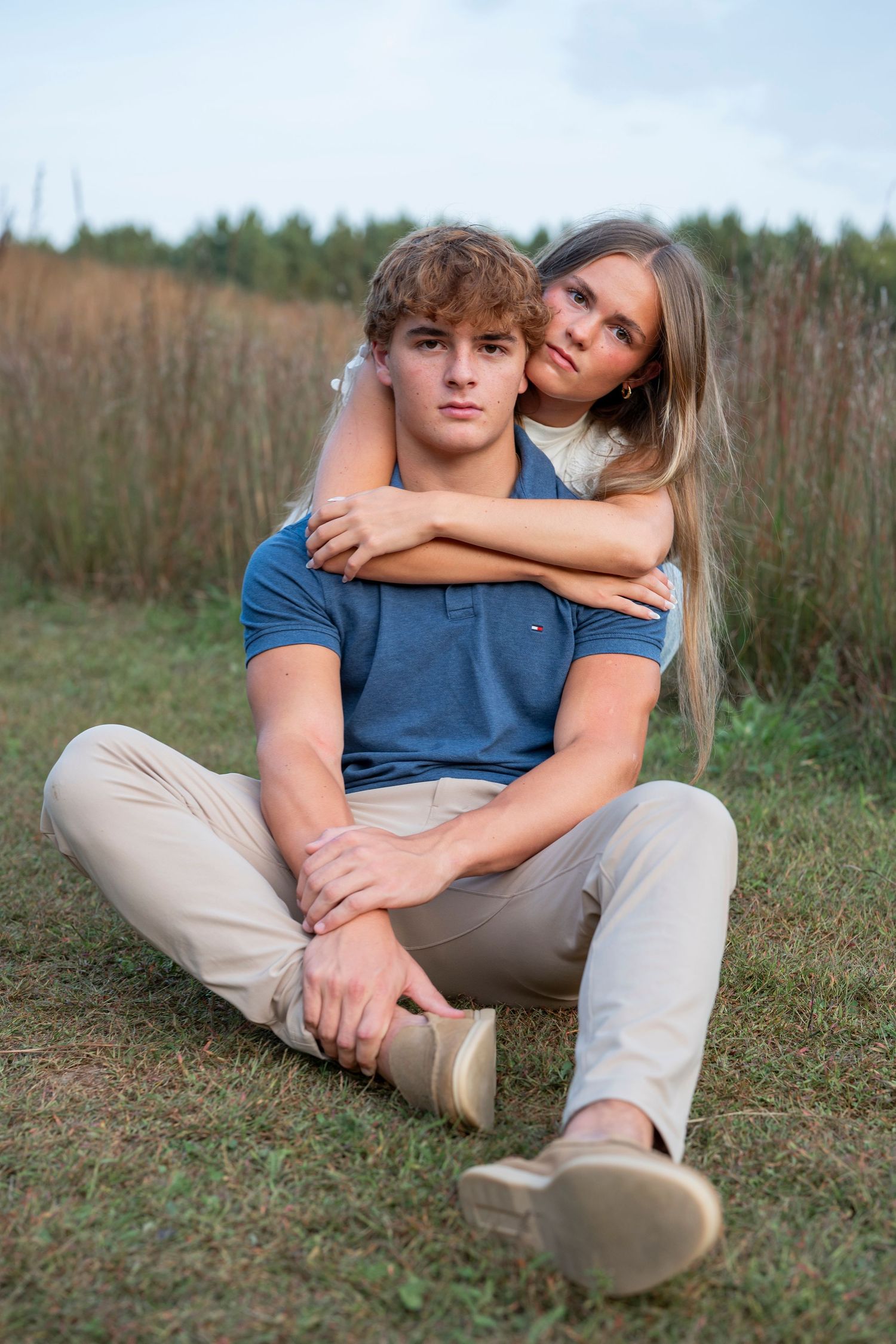A couple relaxes together on grass during an outdoor photoshoot.