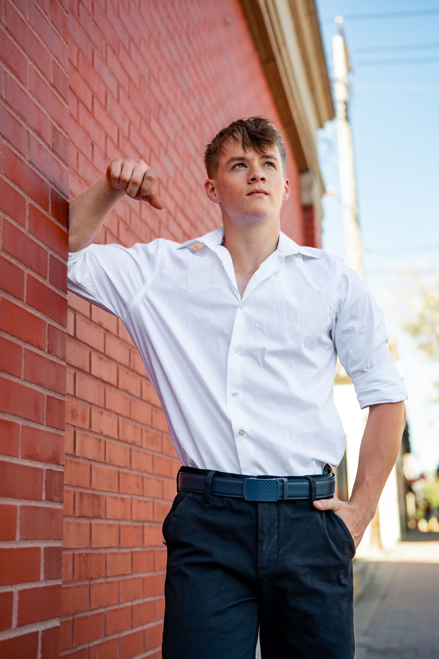 Outdoor fashion shoot featuring crisp white shirt and dark pants against red brick architecture.