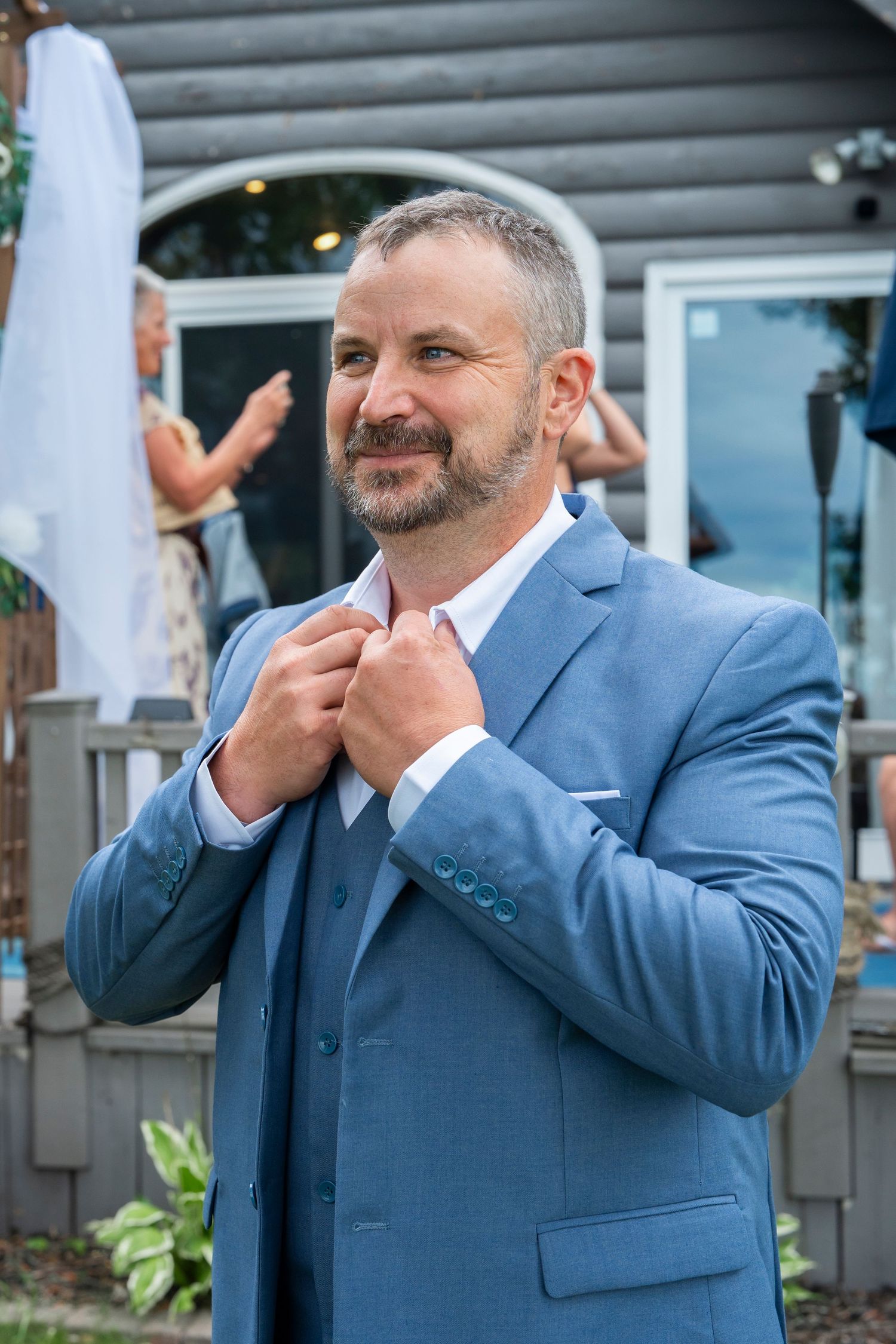 Man in blue suit making emotional gestures during outdoor event.