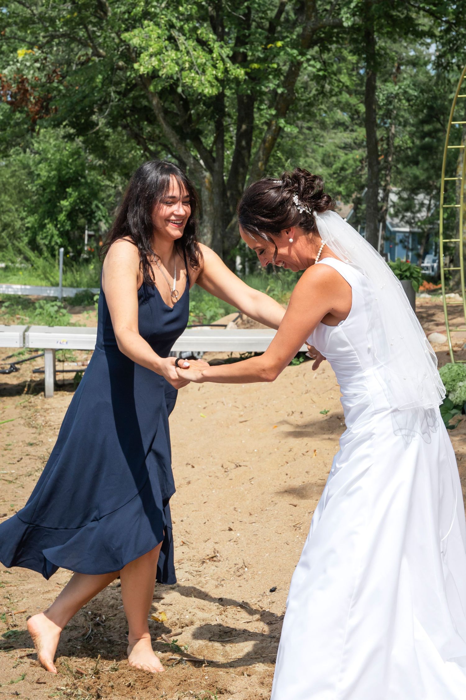 Two women in navy and white dresses dancing joyfully at an outdoor event.