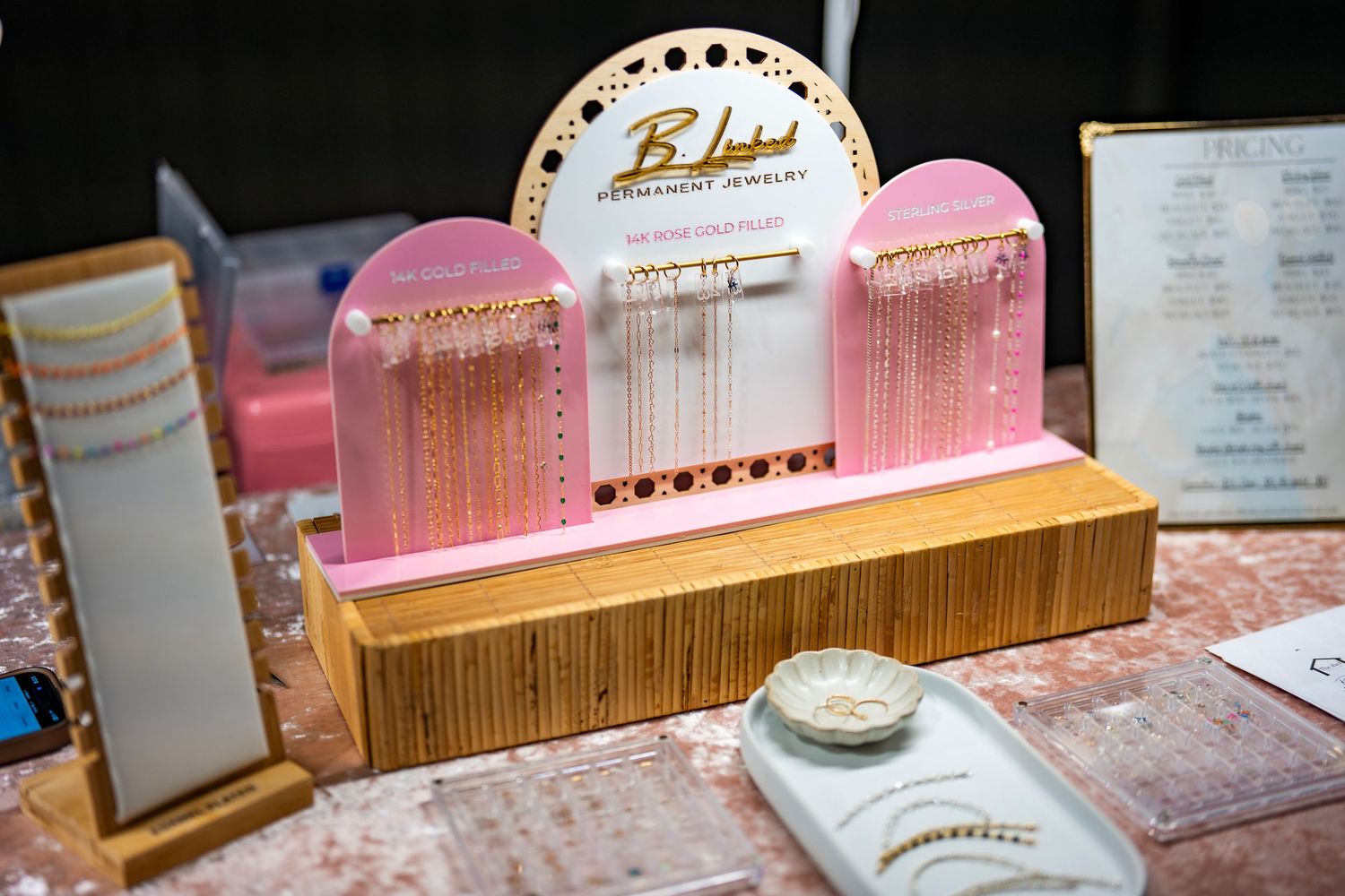 Row of pink decorative display boxes arranged on a wooden shelf with jewelry.