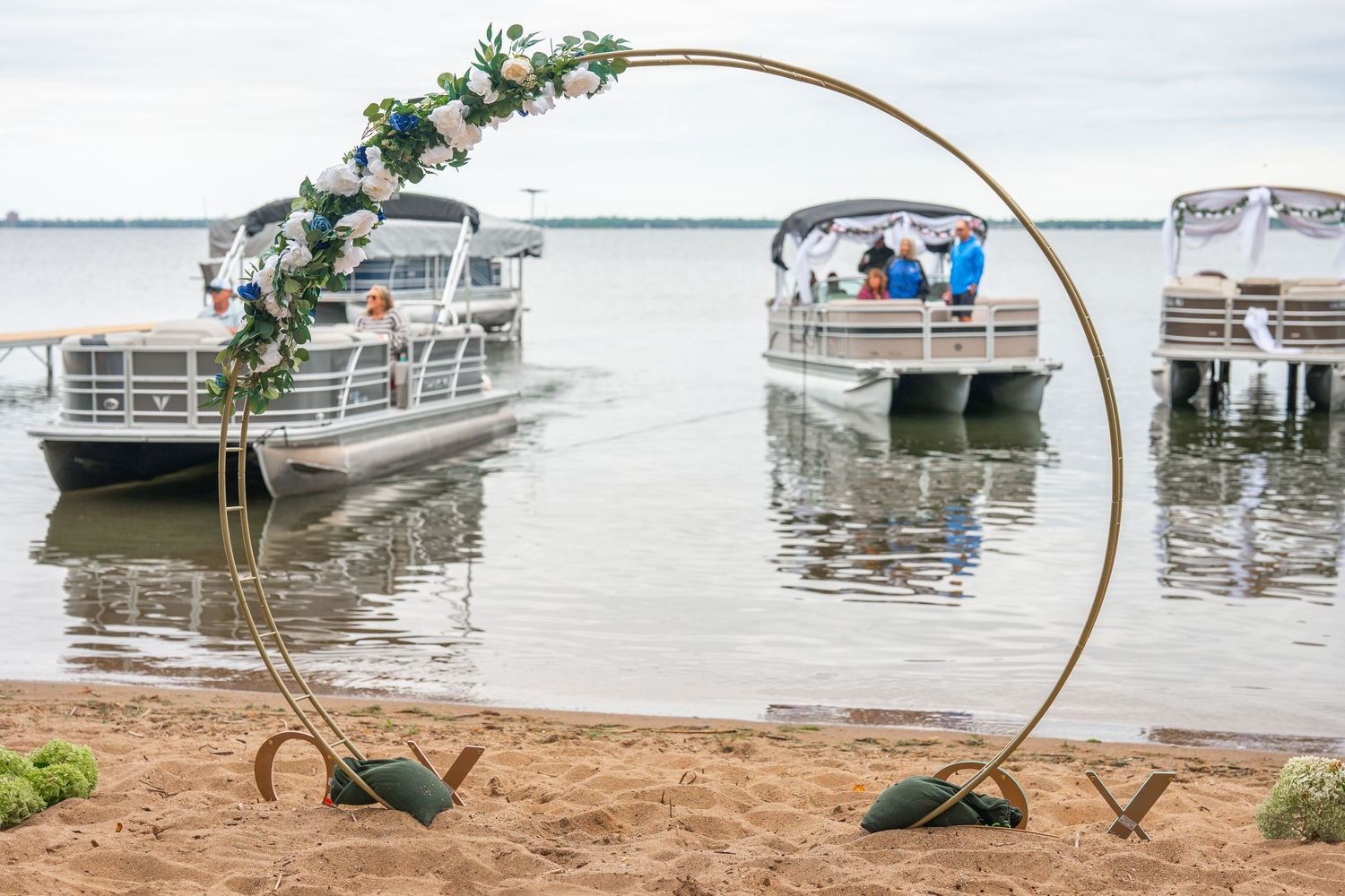 Decorative copper arch with greenery against waterfront setting.