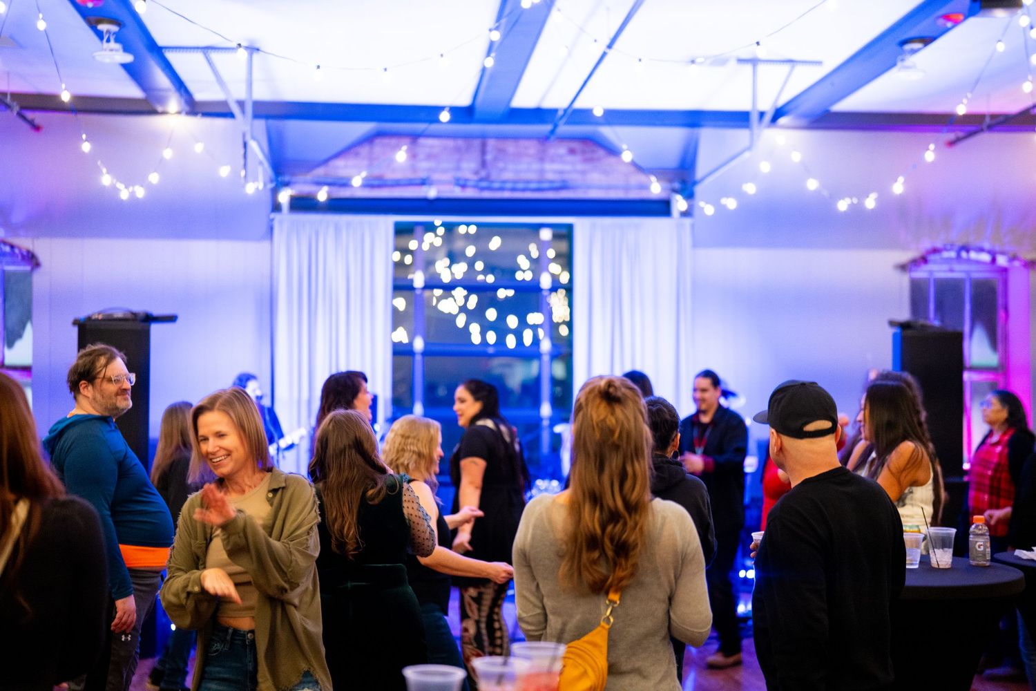 Indoor event space with string lights and guests mingling during evening gathering.