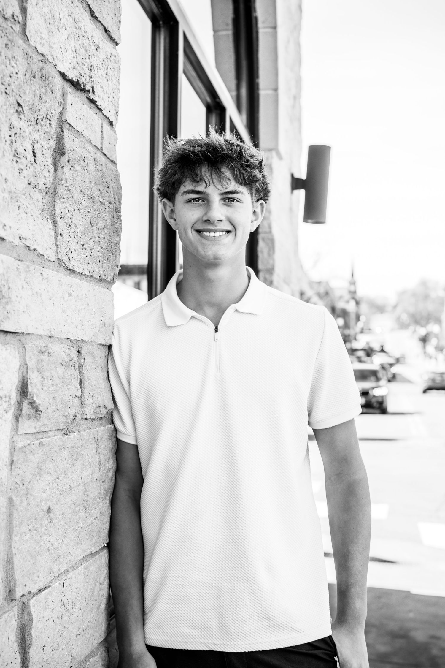 Black and white photo series of someone in a white polo shirt posing against a textured wall.