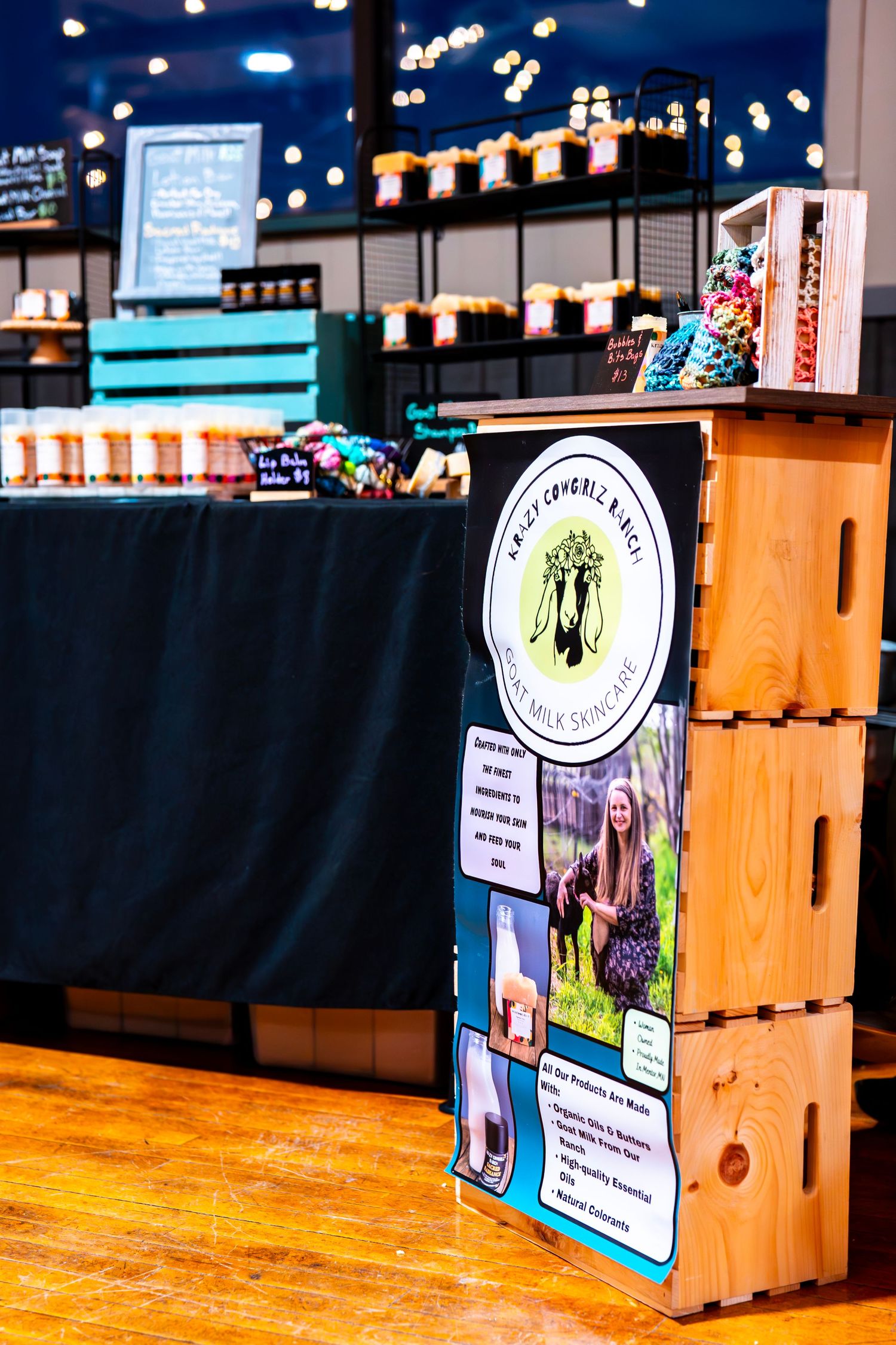 Wooden crate displays with product signage arranged on hardwood flooring at a market.