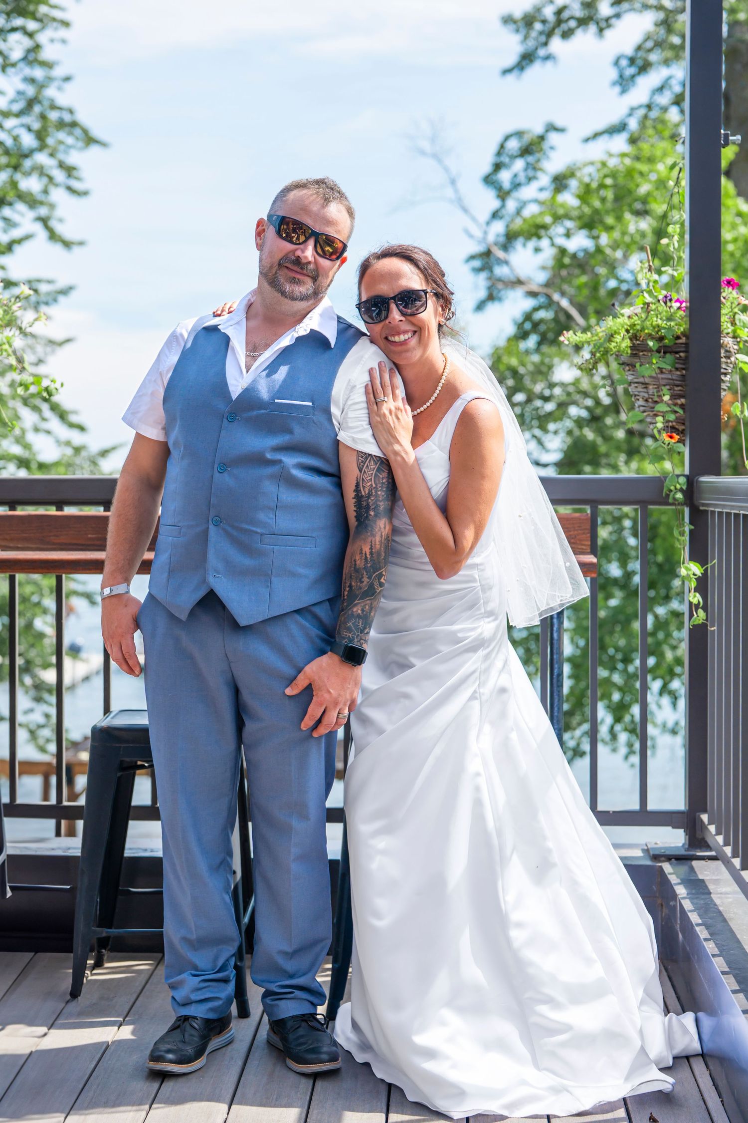 Casual wedding portraits taken on an outdoor deck with lake views in the background.