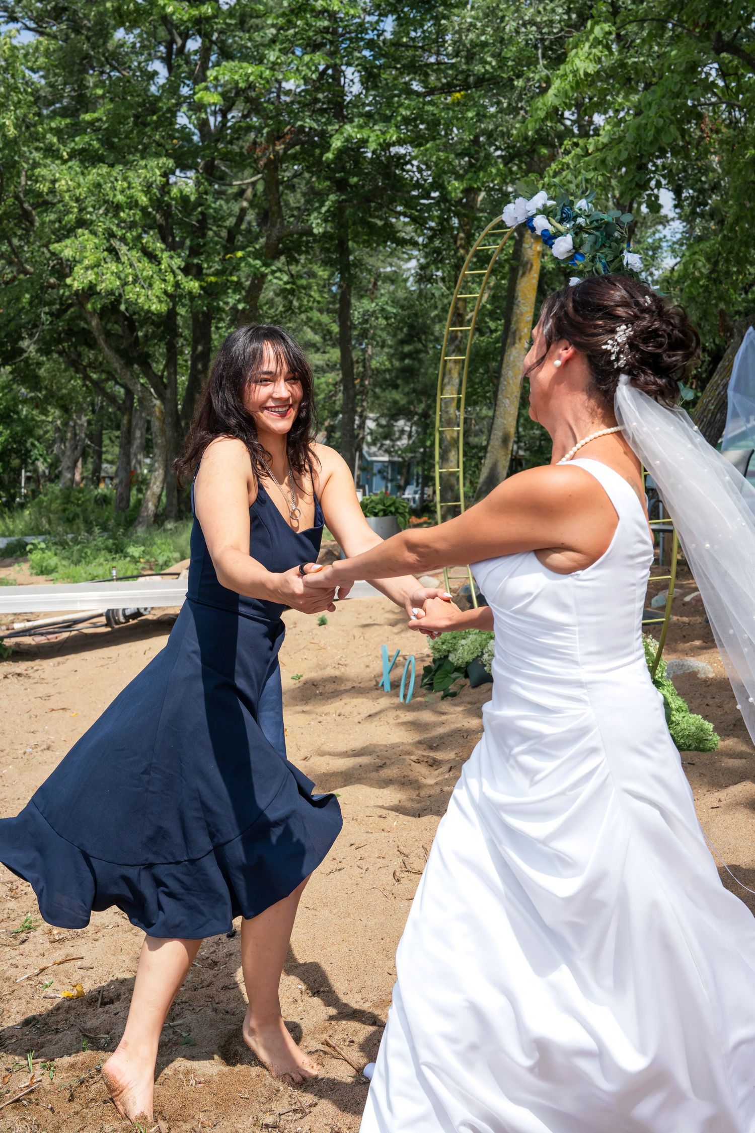 Mom and daughter share a joyful dance moment in a wooded outdoor setting.