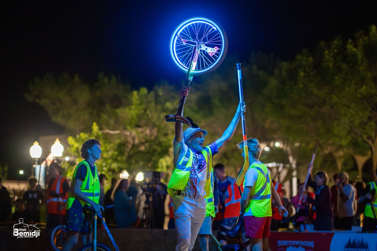 Illuminated bicycle wheels creating blue light trails against dark night sky.