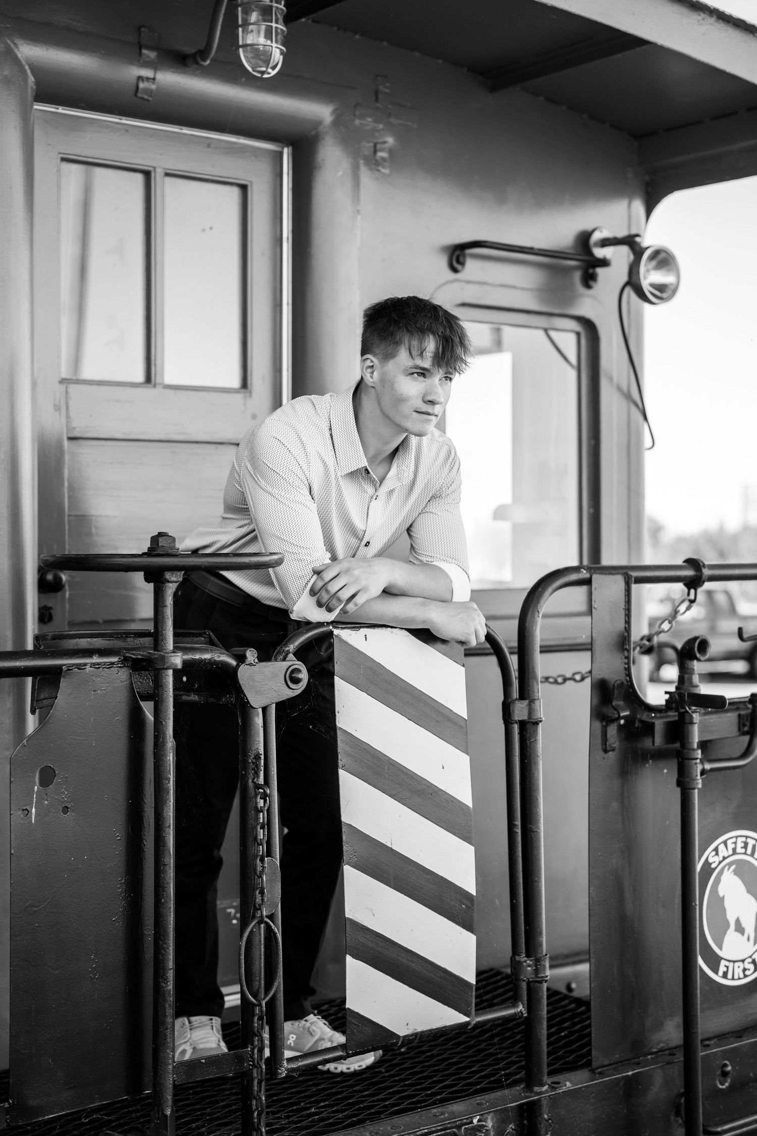Black and white photo of someone posing on vintage train car platform.
