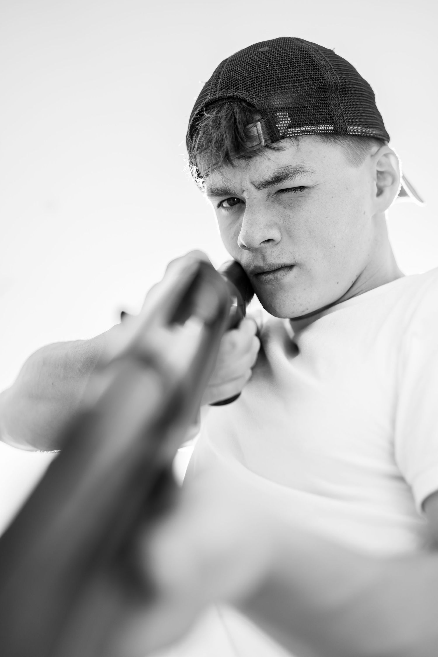 Black and white close-up of person in cap looking down rifle barrel.
