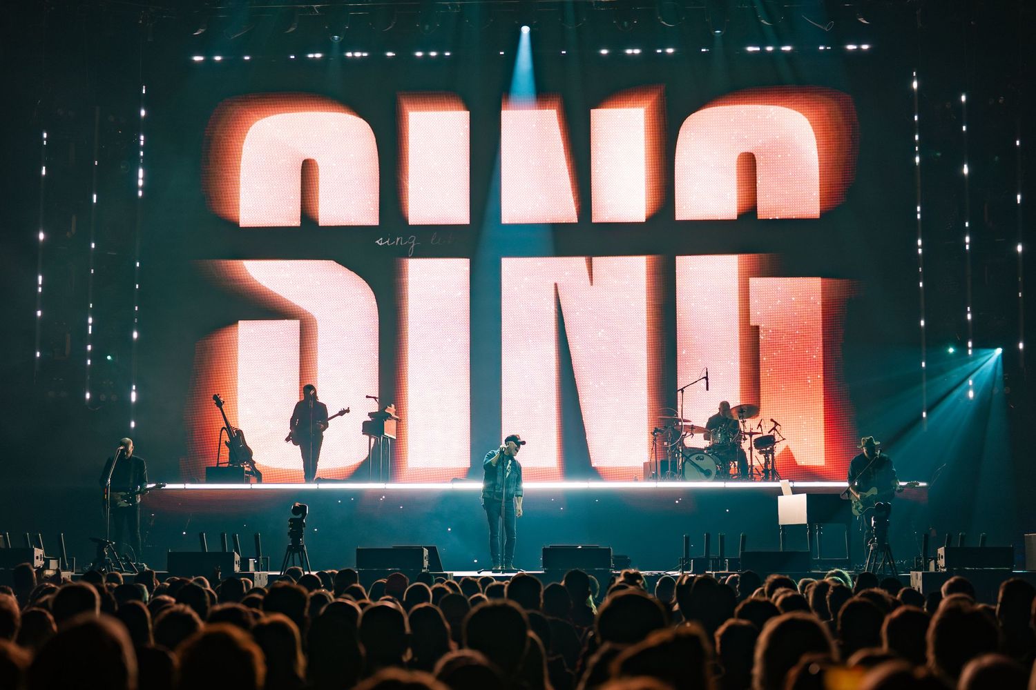 Large concert venue with illuminated text displays and dramatic stage lighting effects.