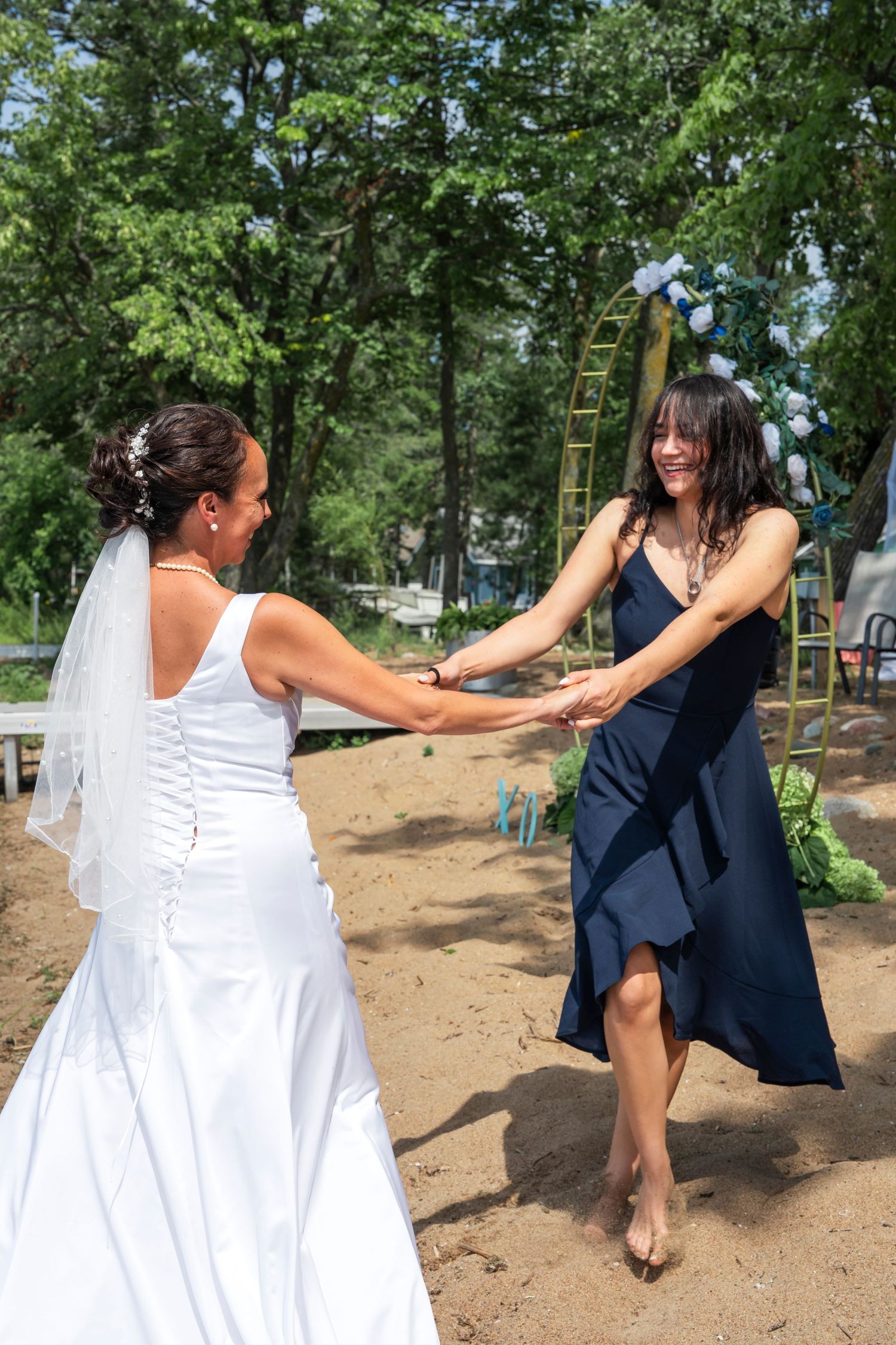 Mom and daughter share a joyful dance moment in a wooded outdoor setting.