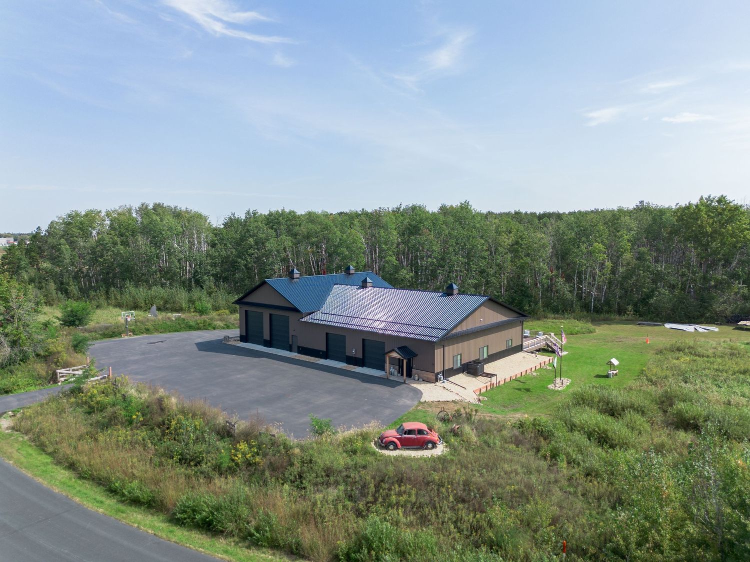 Aerial perspective of rural buildings and paved roads winding through green countryside.