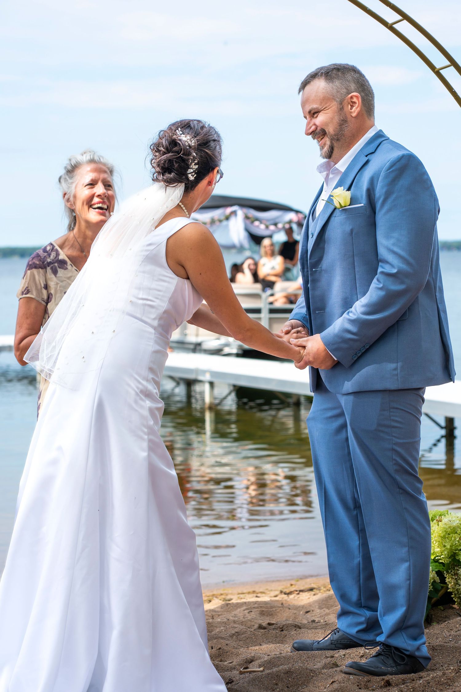 Wedding ceremony candid moments under copper arch by waterfront.