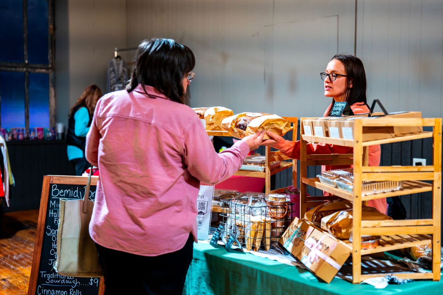 Retail display tables with merchandise arranged under warm lighting at an indoor market.