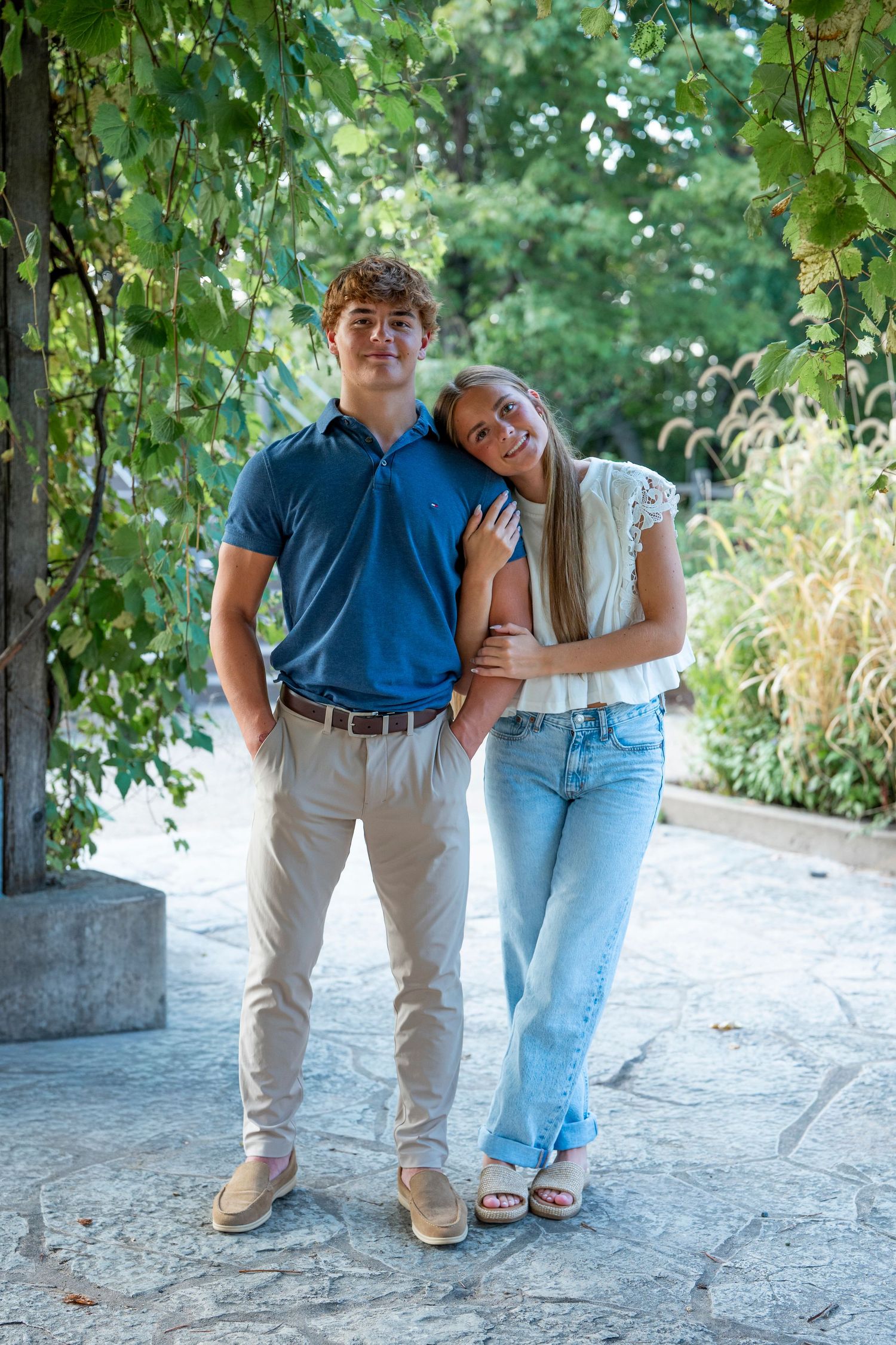 A couple standing together under a vine-covered archway.