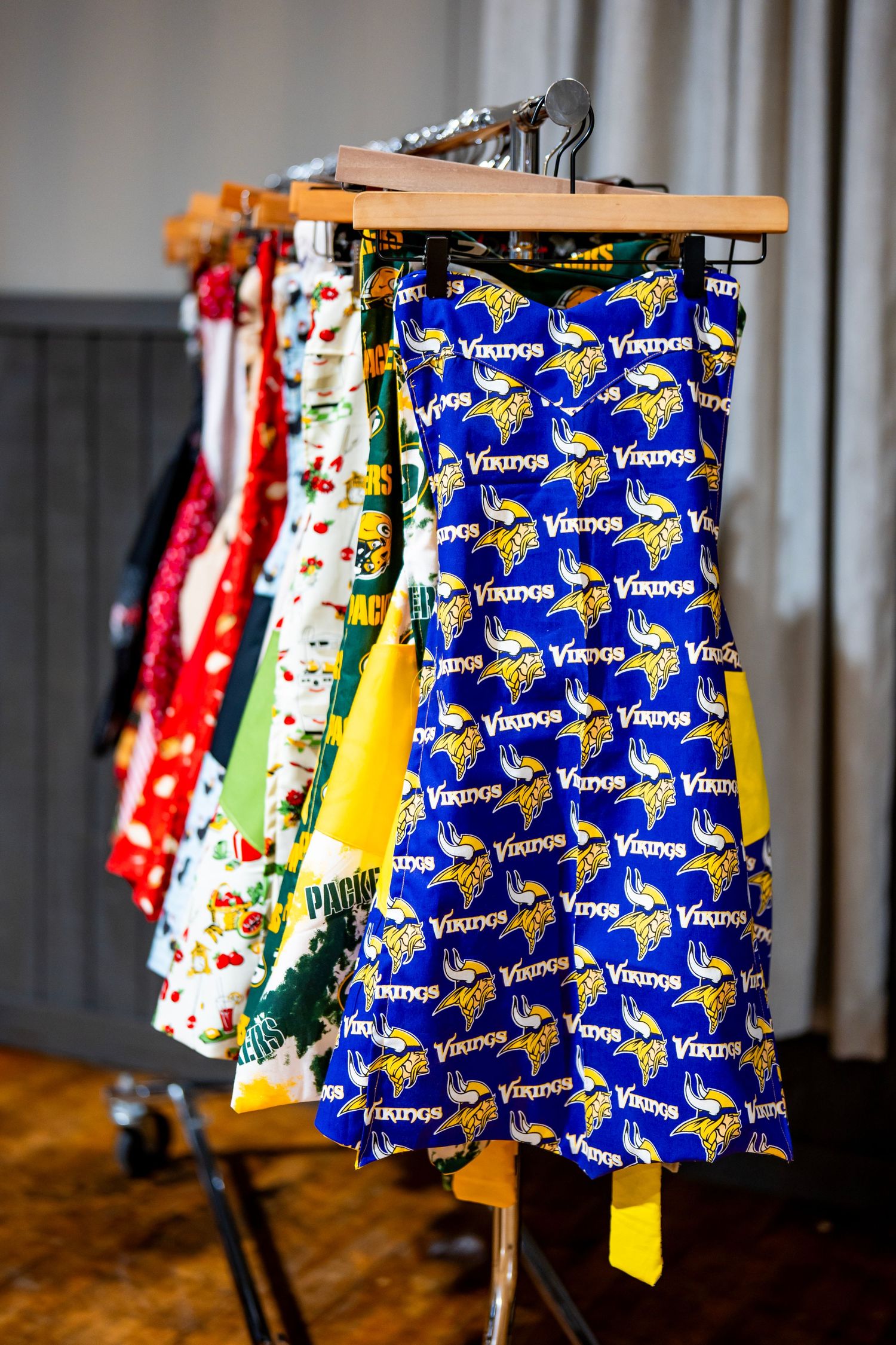 Colorful Minnesota Vikings themed apron displayed on hangers in a retail setting.