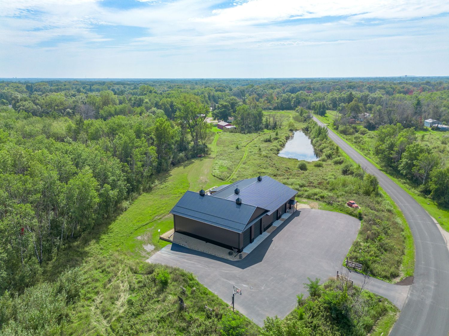 Drone shot of a large commercial property with parking lots surrounded by green landscape.