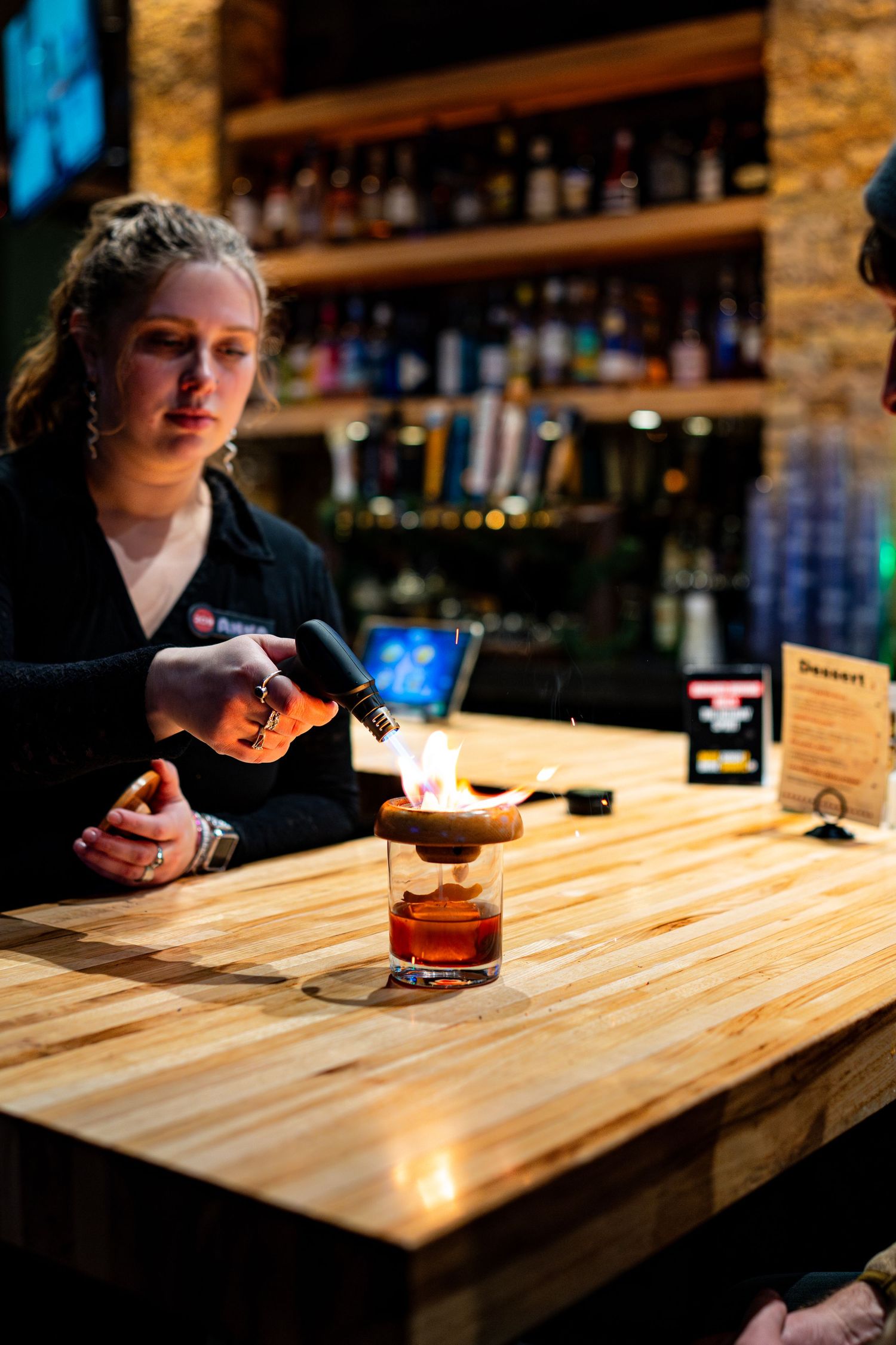 Wooden bar top with cocktail glasses in warm ambient lighting.
