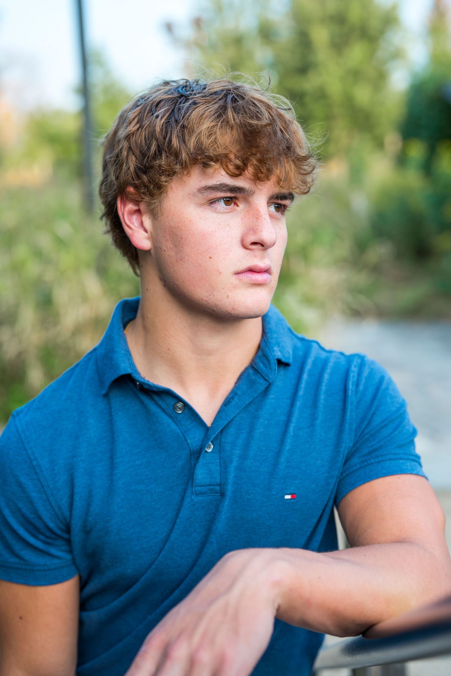 Casual senior outdoor portrait series in blue polo against natural background.