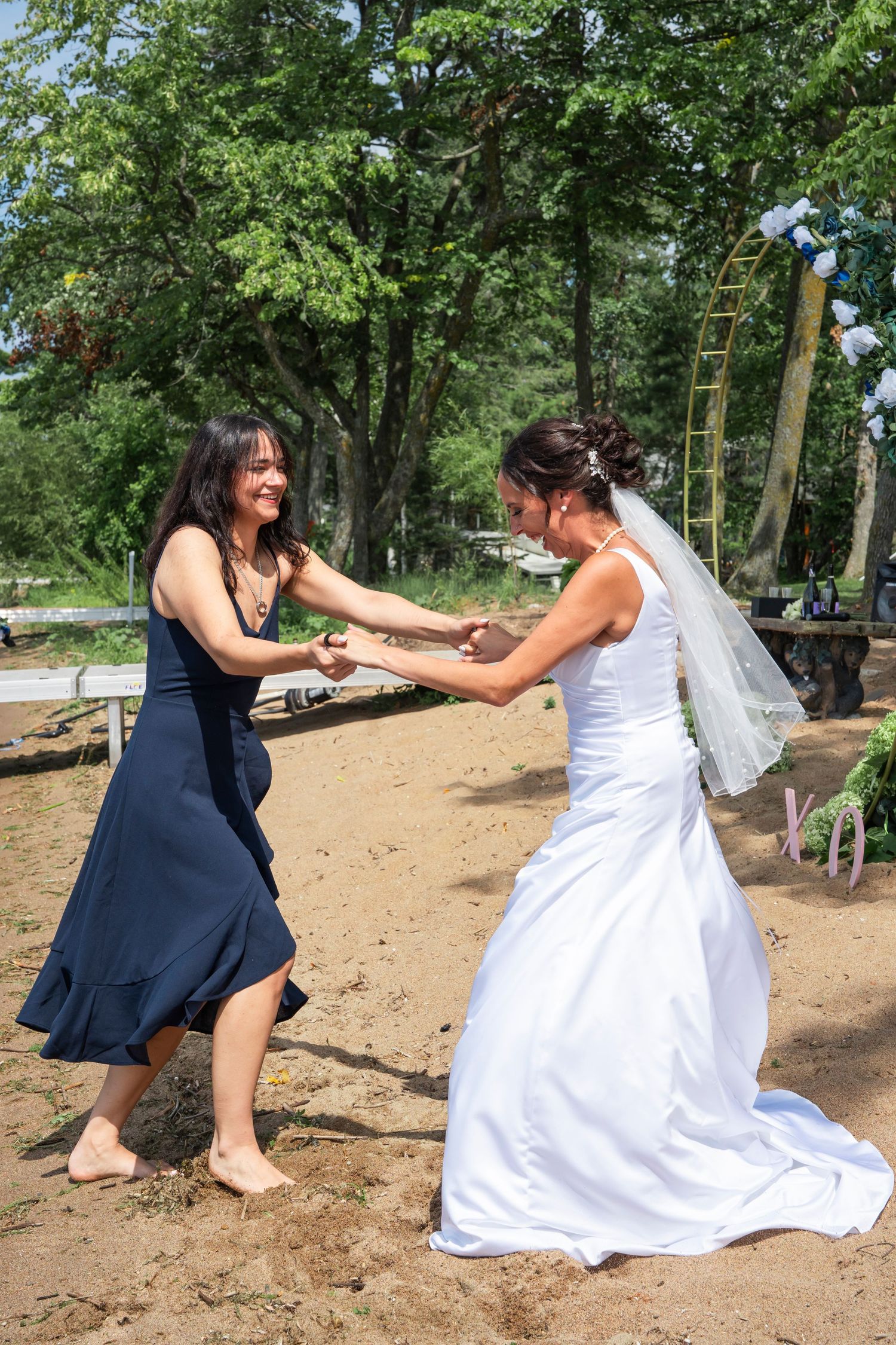 Mom and daughter share a joyful dance moment in a wooded outdoor setting.