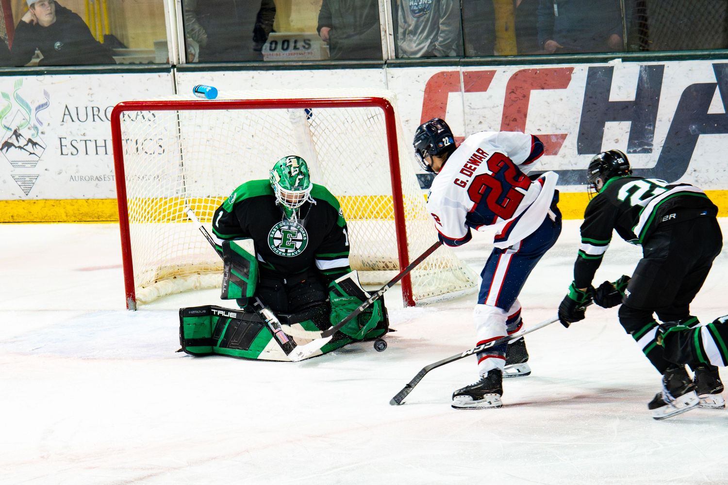 Hockey players battling for the puck near the goal during a competitive match.