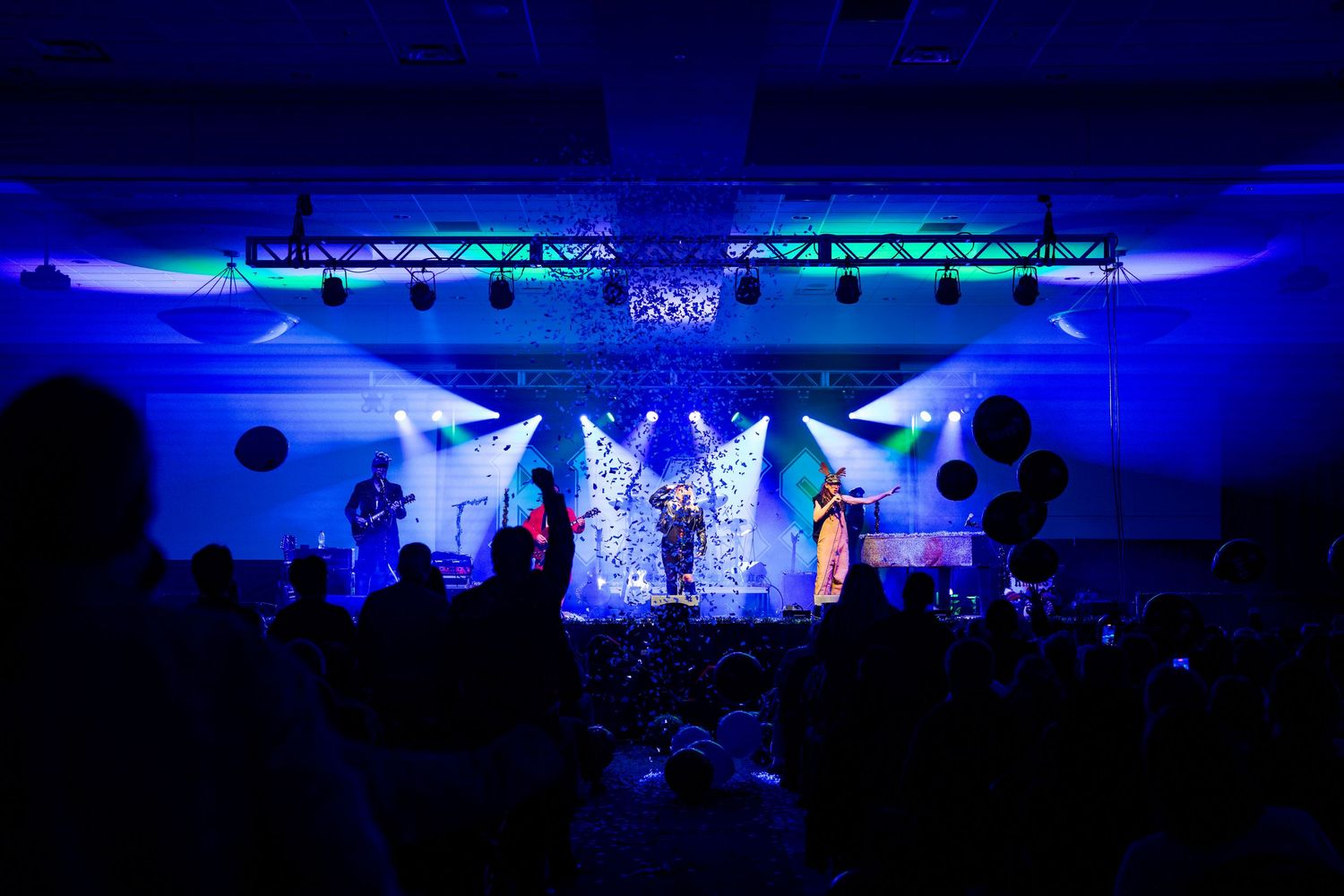Concert venue with dramatic blue lighting and silhouetted audience members.