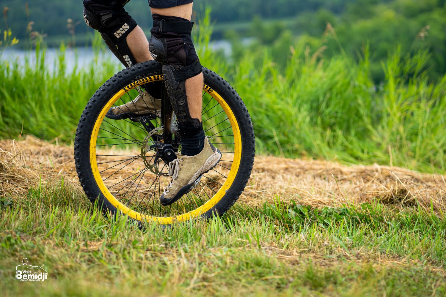 Close-up of unicycle tires riding over dirt trails and grass in an outdoor course.