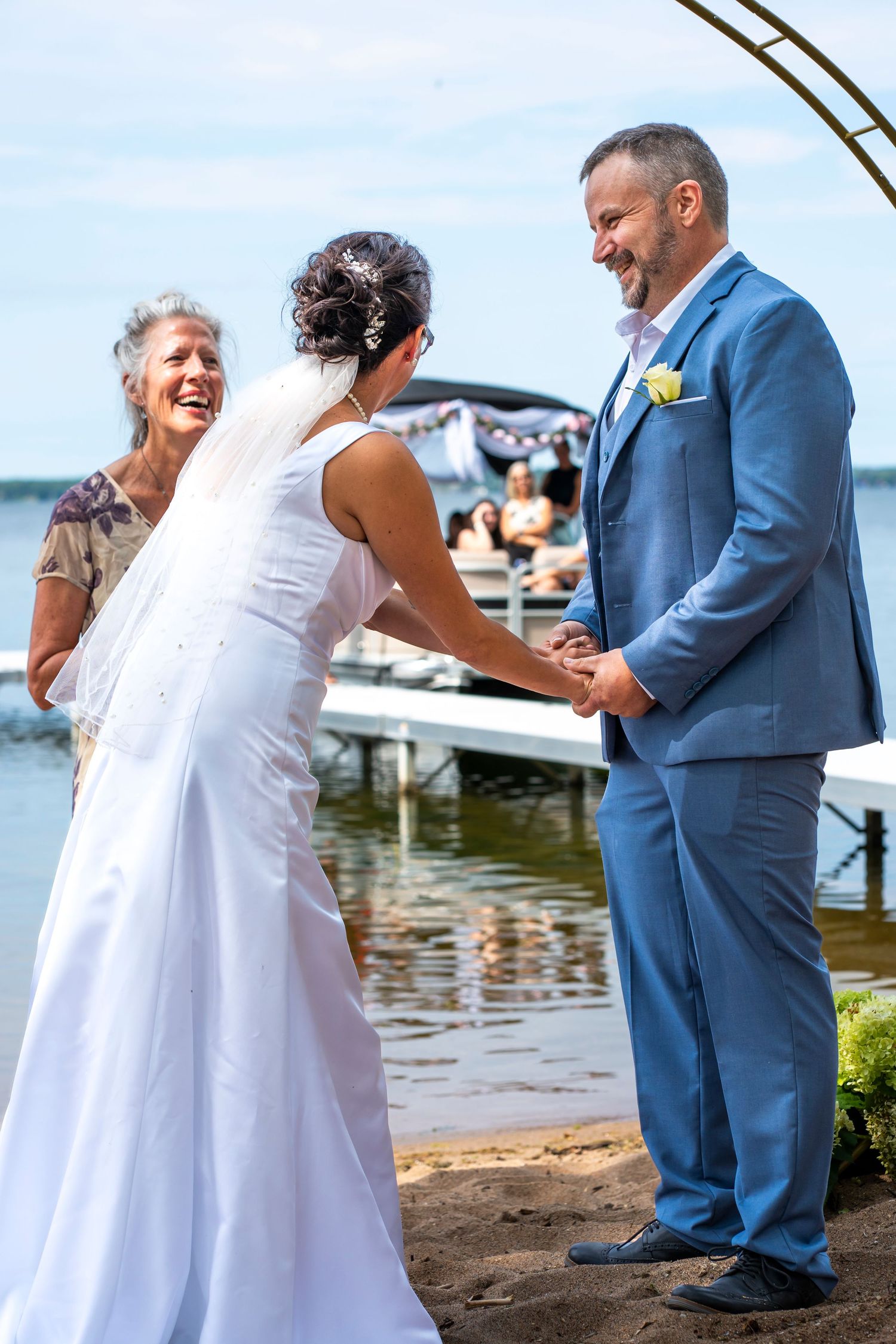 Wedding ceremony taking place by a waterfront with boats in the background.