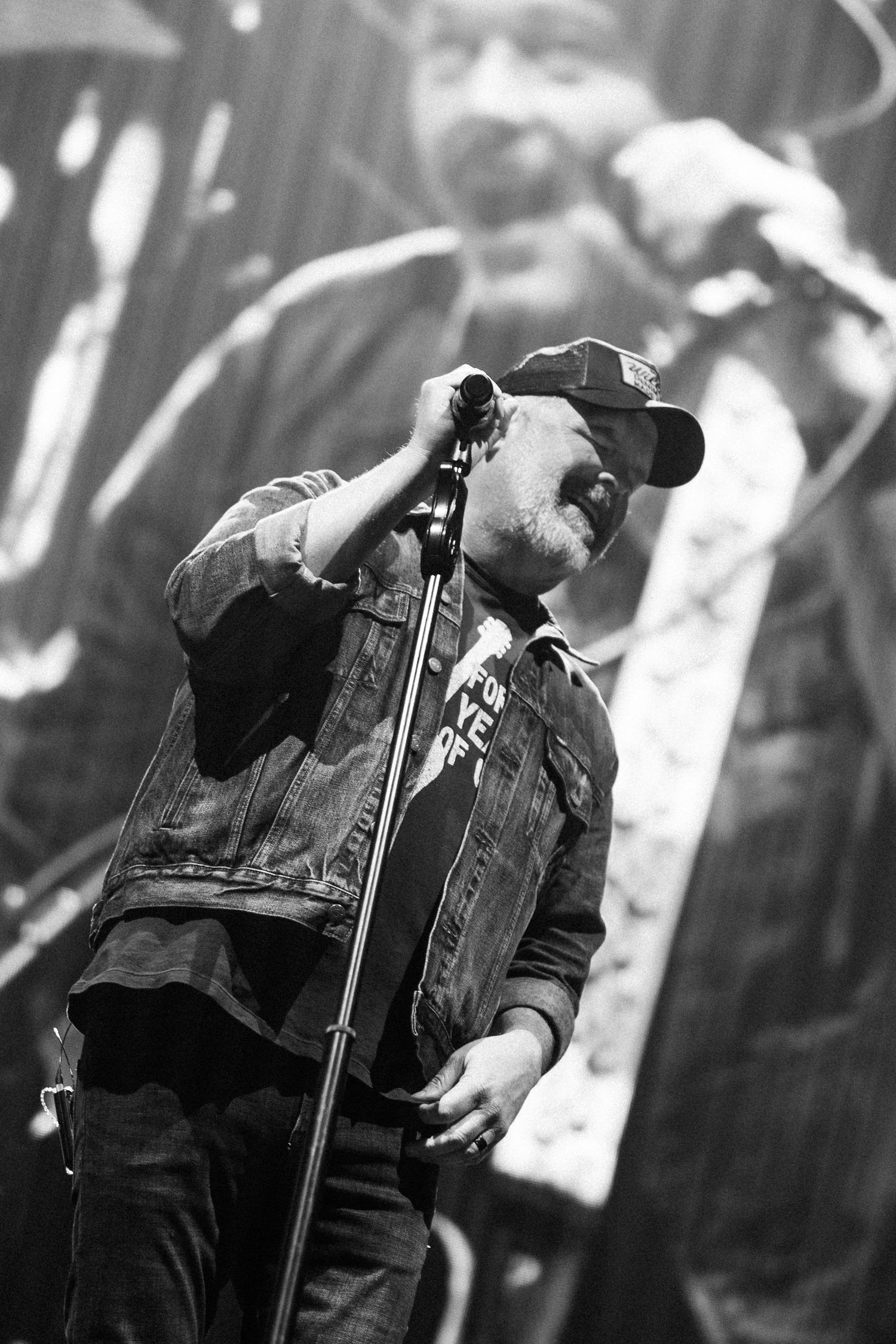 Black and white photo of musician performing passionately on stage with microphone.