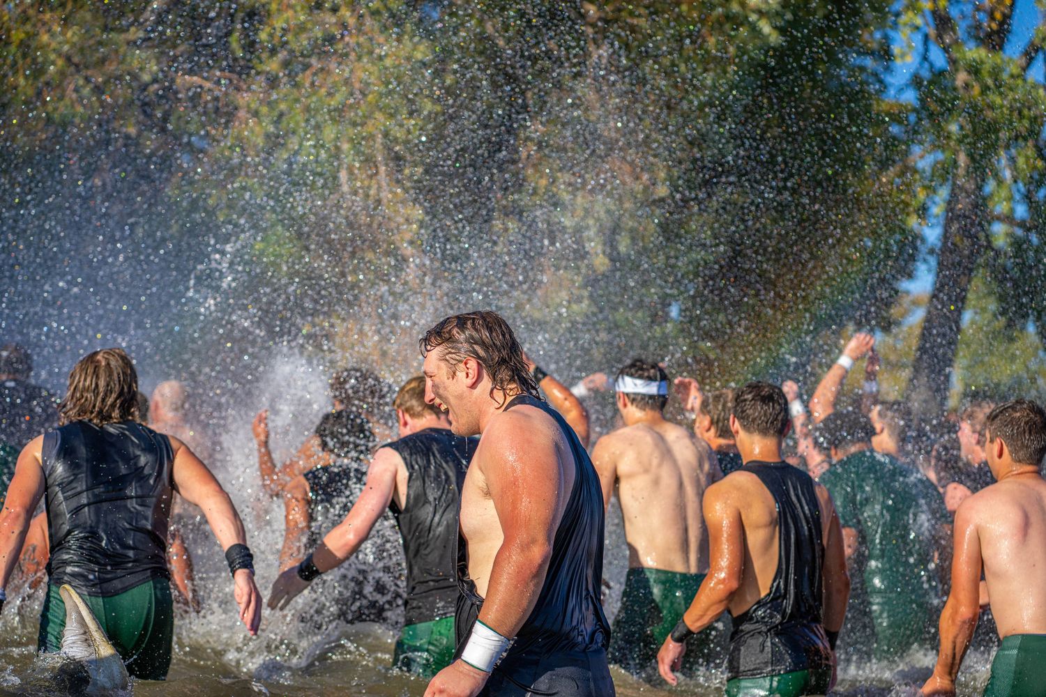 Large group celebrating outdoors with water splashing in the sunlight.