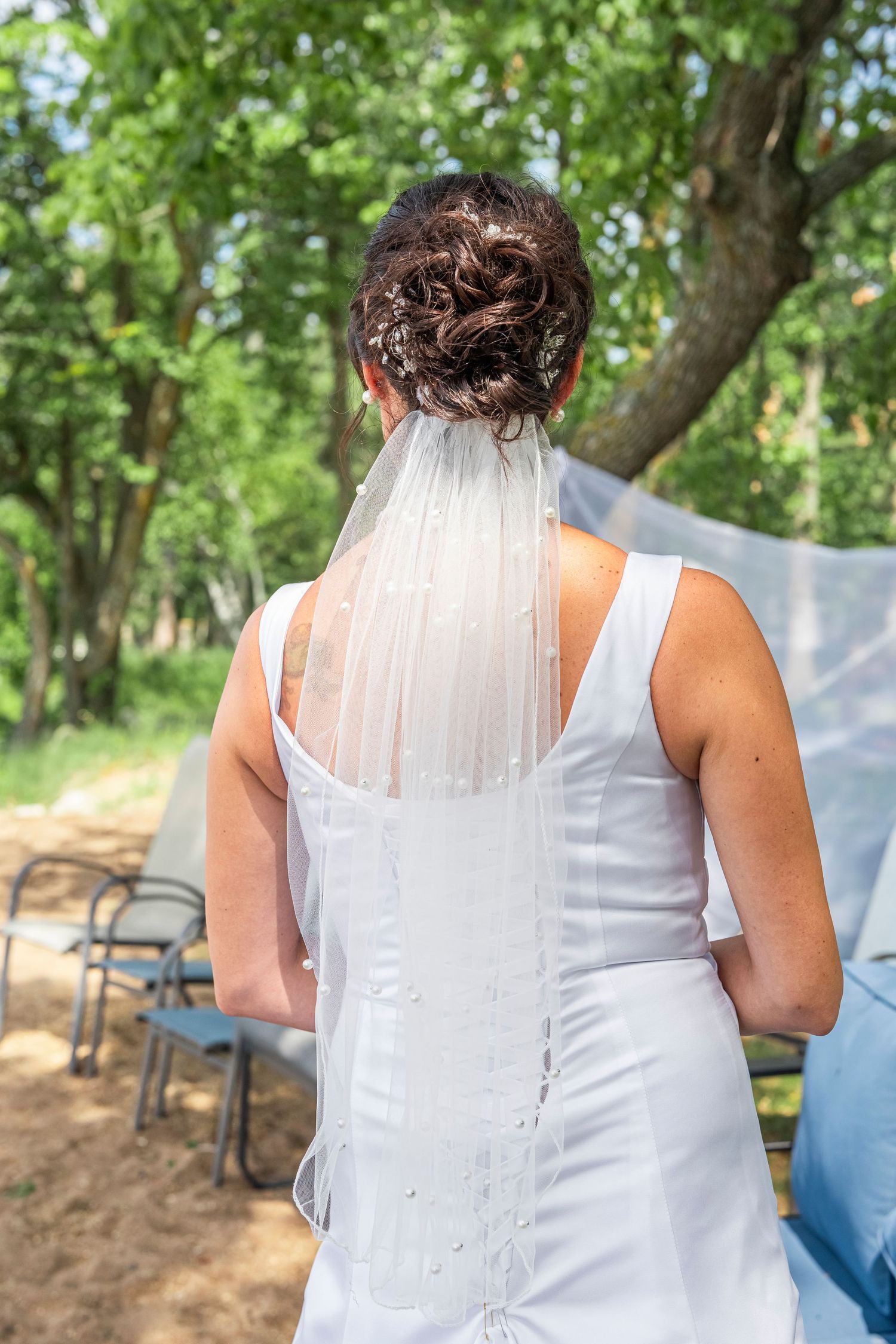 Close-up back view of a white wedding dress with buttons and veil details.