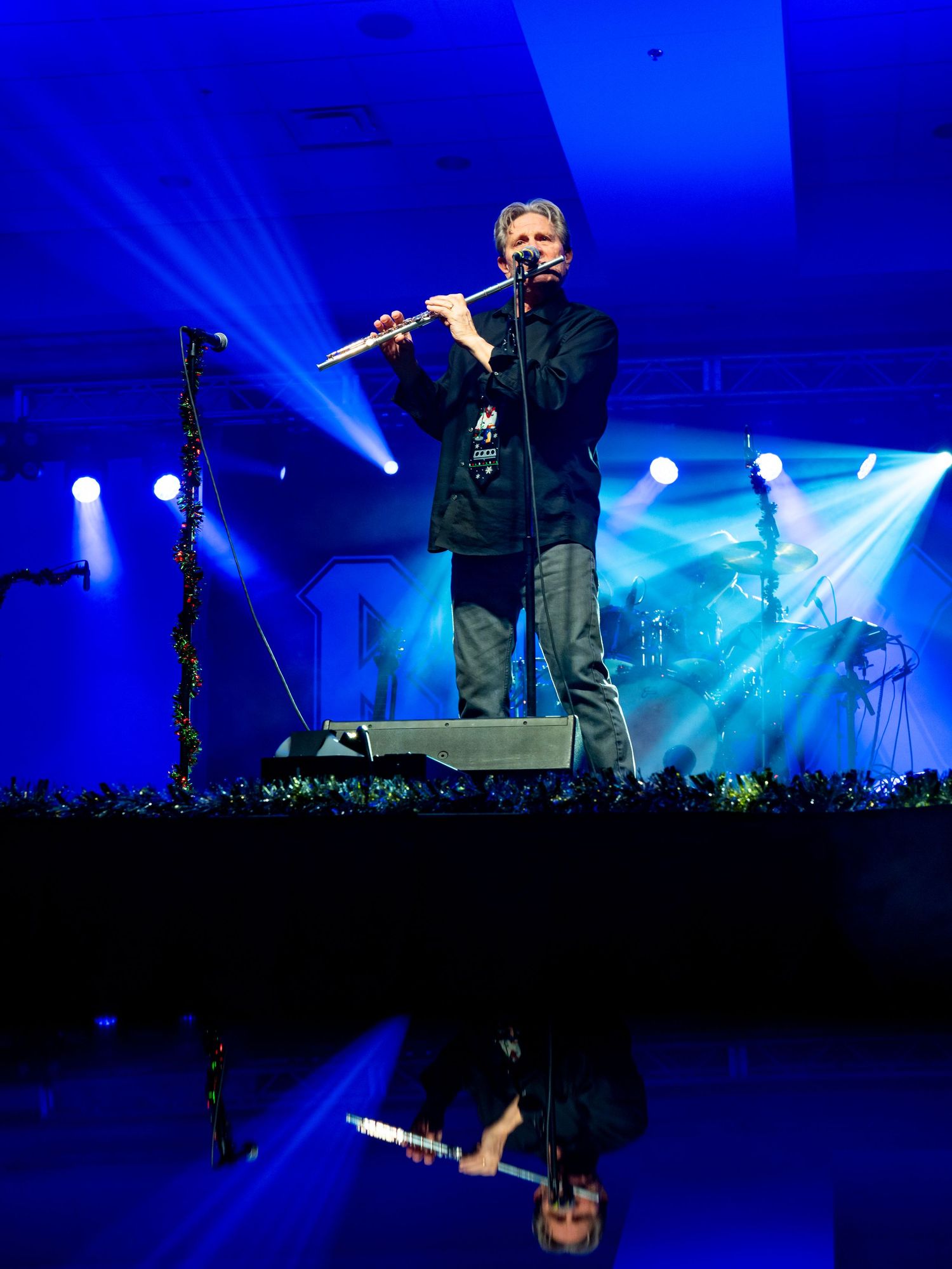 Concert flute performance on dark stage with dramatic blue lighting effects.