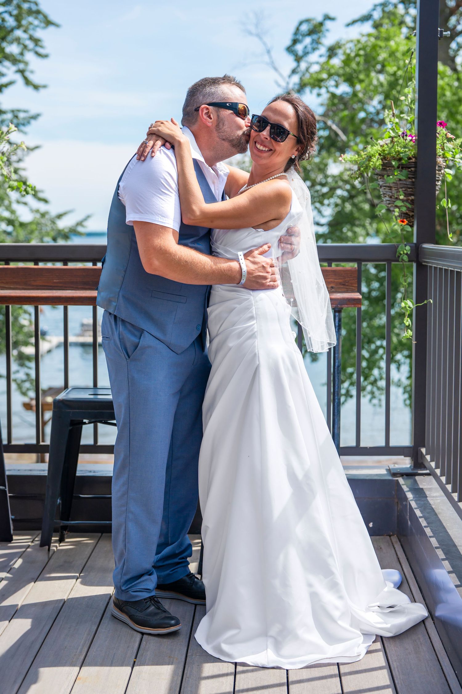 Wedding couple shares intimate moments on a wooden deck overlooking a scenic lake view.