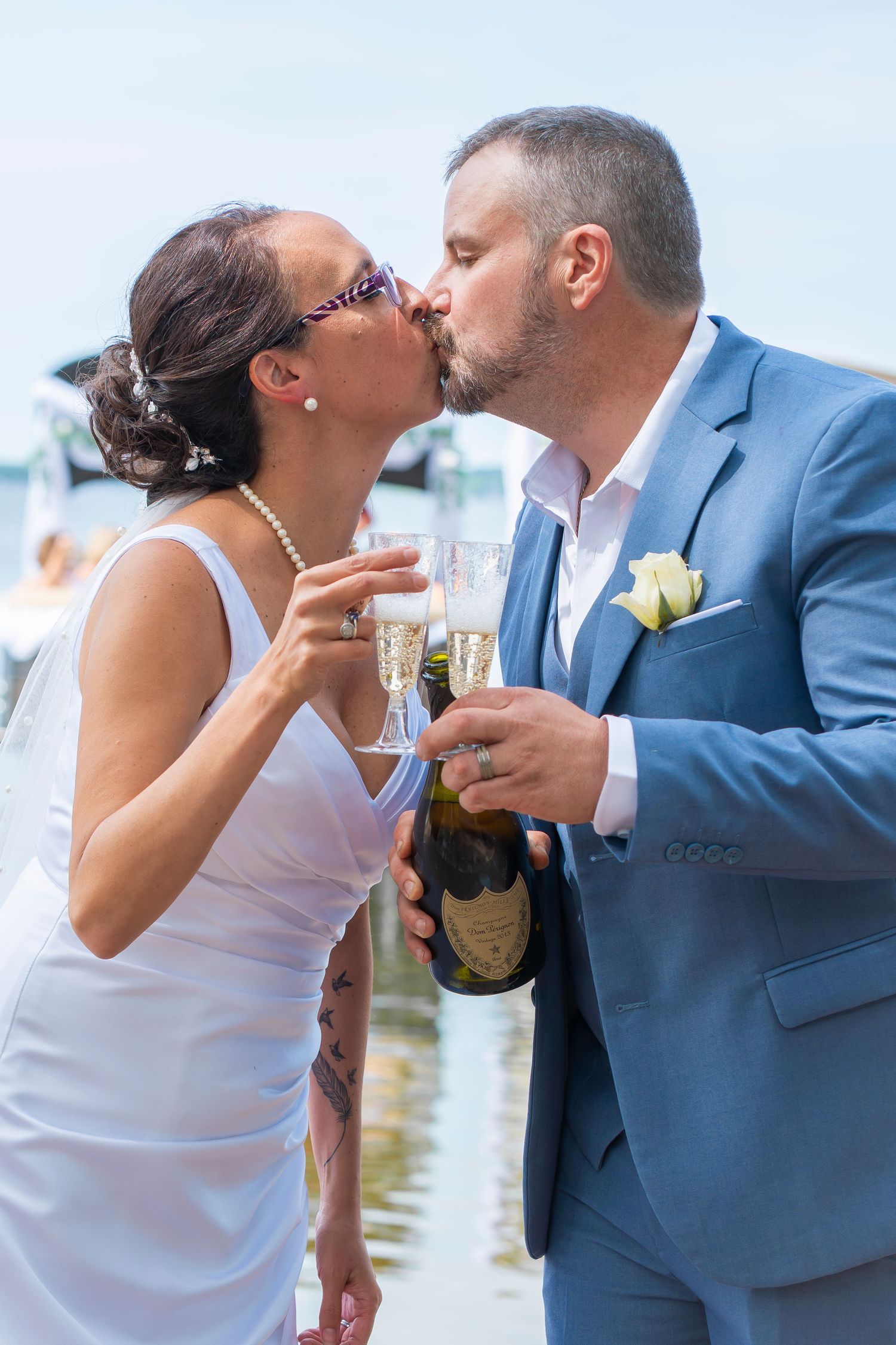 Newlyweds share champagne toast during lakeside celebration.