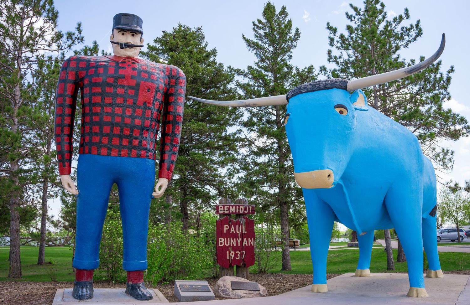 Panoramic view of Paul Bunyan and Babe the Blue Ox statues in a park setting.