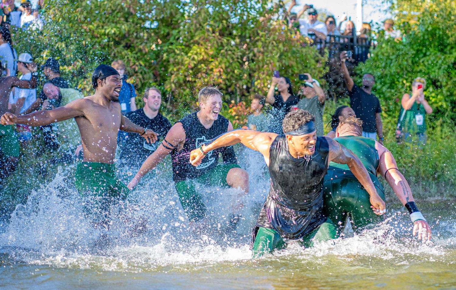 Panoramic view of crowd playing and splashing in water after football game.