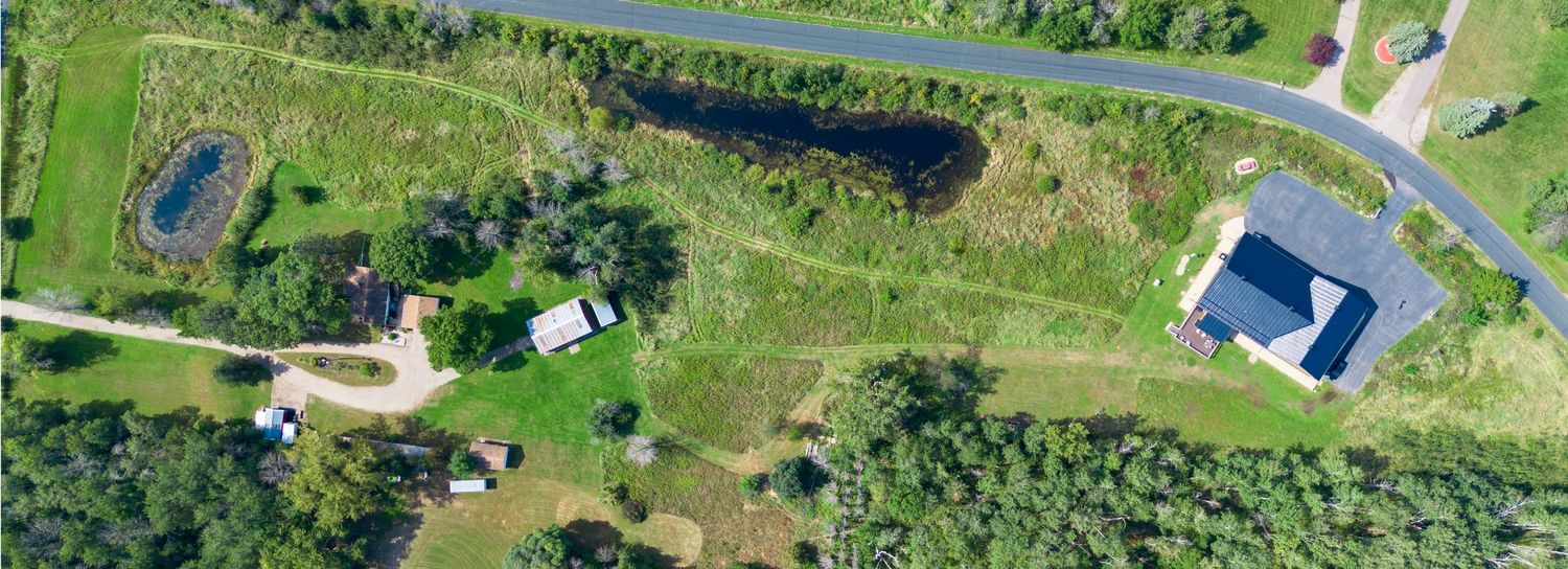 Bird's eye view of rural landscape showing scattered buildings and winding roads among green fields.
