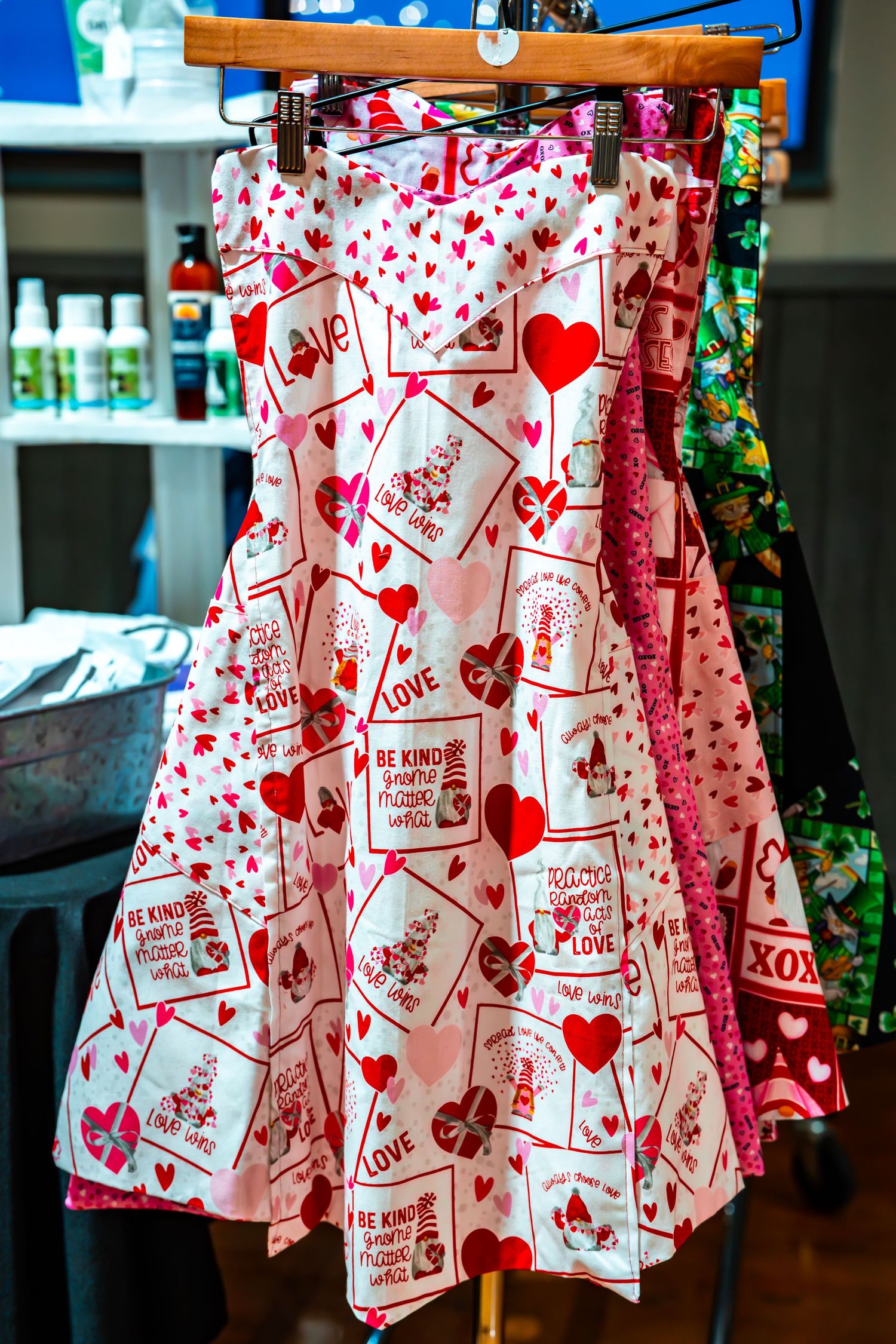 Heart-patterned Valentine's Day clothing displayed on retail racks with festive decorations.