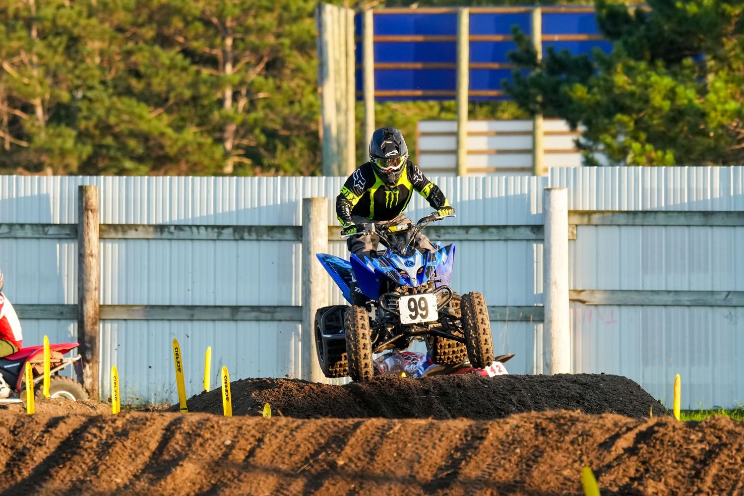 Dirt bike racers navigating a challenging outdoor motocross track with jumps and turns at County Fair.