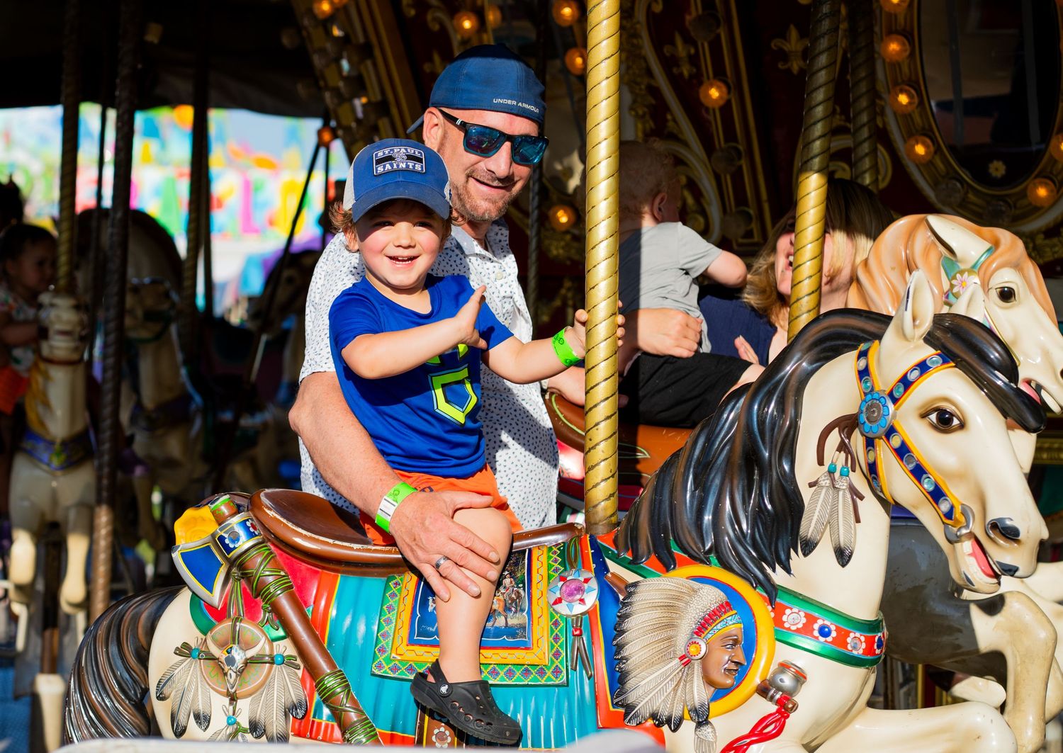 Colorful carousel horses decorated with ornate details spin on a vintage merry-go-round.